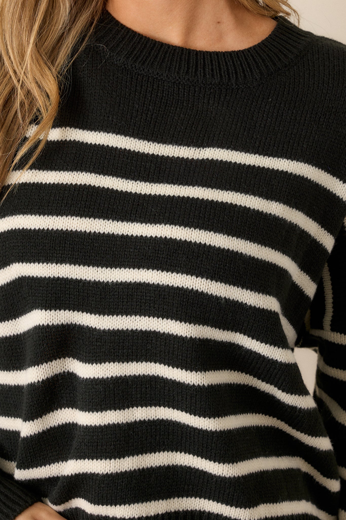 A front-facing view of the sweater, emphasizing the contrast between the black and ivory horizontal stripes and the ribbed neckline.