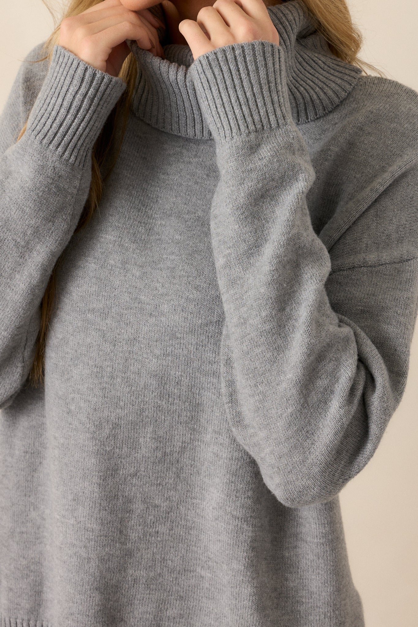 Close up of the ribbed cuffs and ribbed turtleneck on this grey knit, long sleeve sweater. 