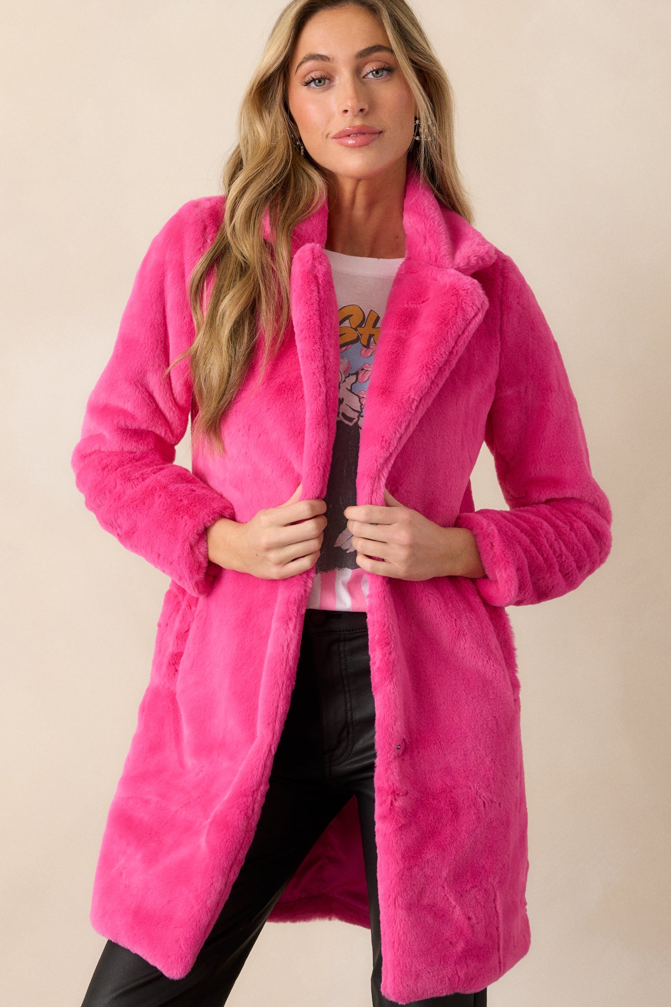 A full view of the hot pink coat, showcasing the v-neckline with notched lapels, fluffy faux fur exterior, and long sleeves.