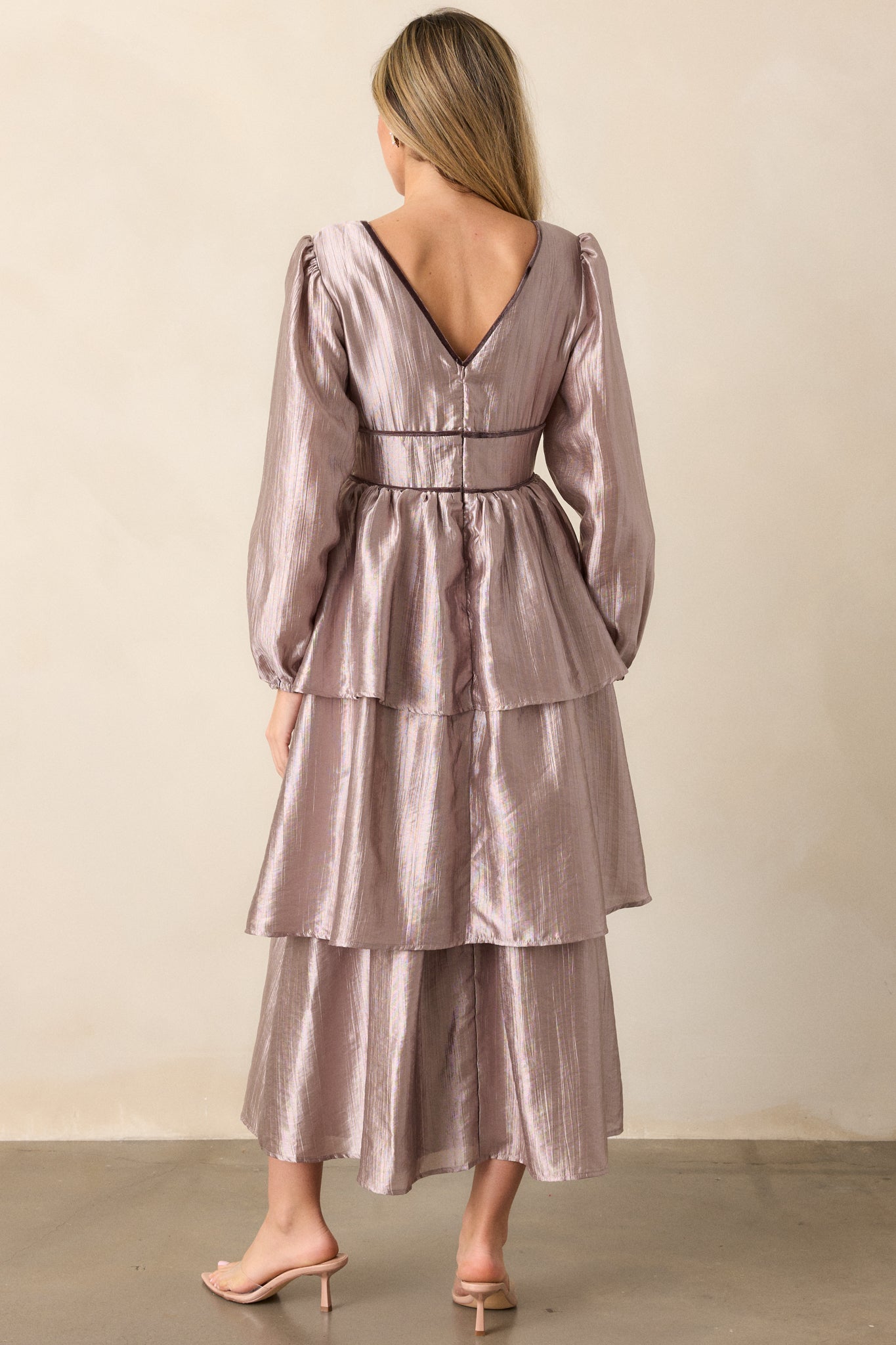 View of the back of the dress, featuring the discrete back zipper, the continuation of the tiered skirt, and the full length of the lantern sleeves.