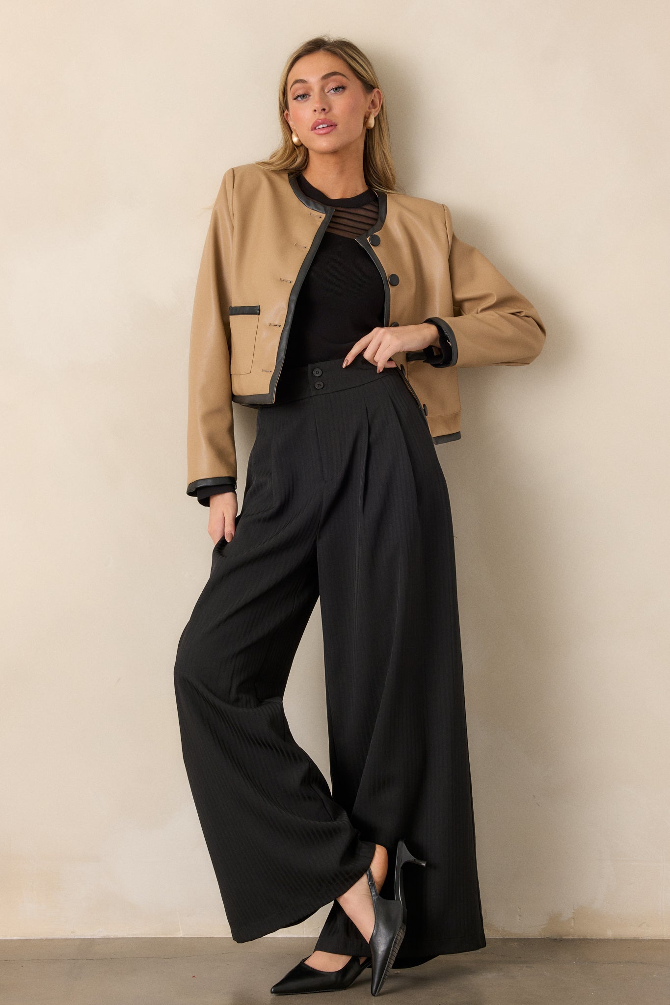 Front view of the black trousers, highlighting the high-waisted design, wide-leg cut, and subtle gray stripe pattern.