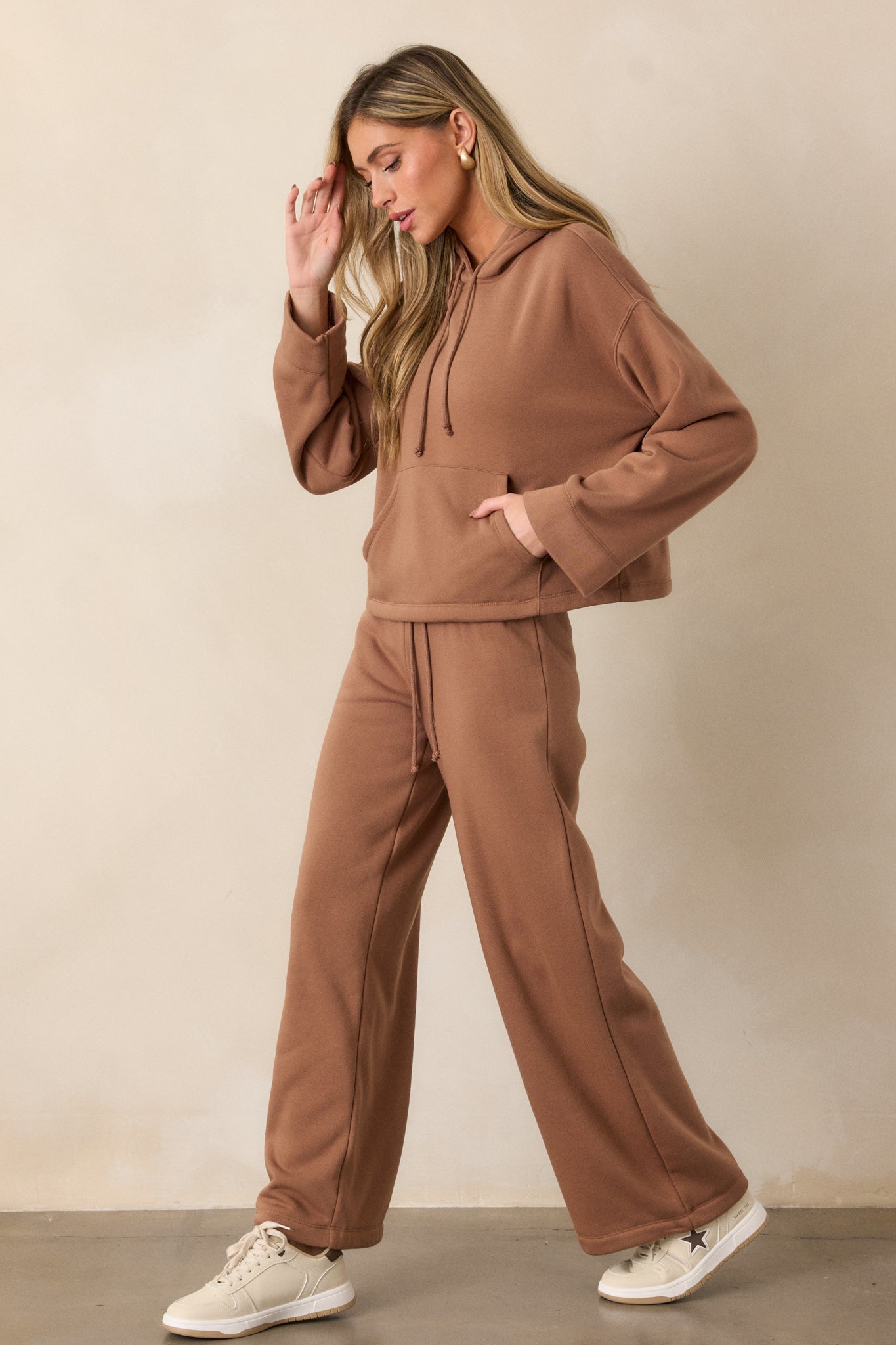 A full view of the brown sweatpants, highlighting the relaxed wide-leg silhouette and smooth fabric finish.