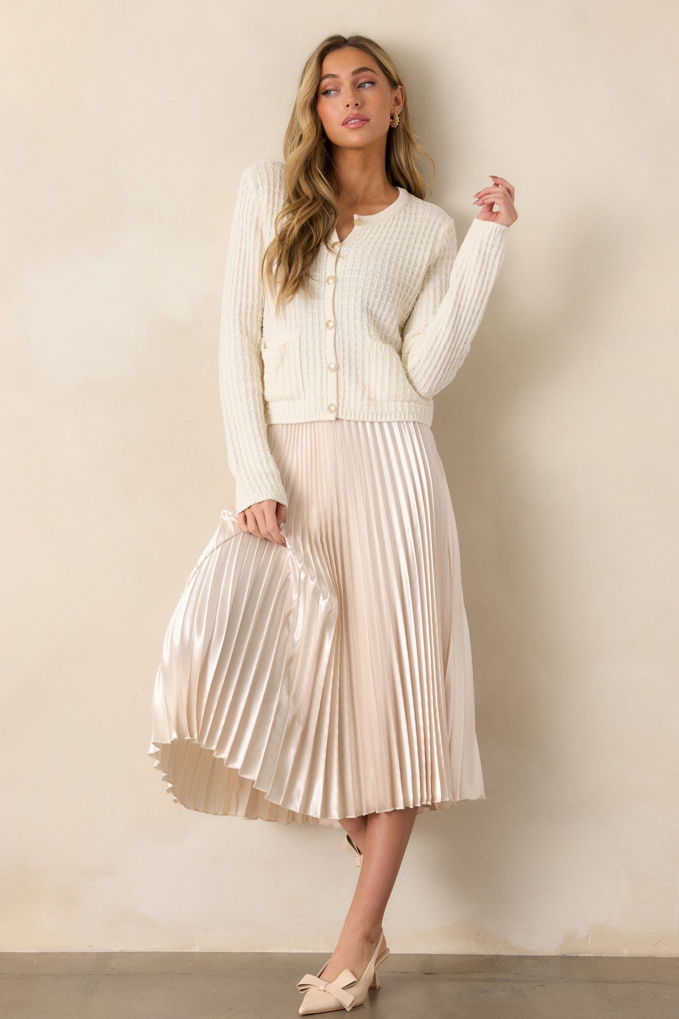 This ivory midi skirt features a high waisted design, an elastic insert at the back of the waist, a discrete side zipper, and is heavily pleated throughout.