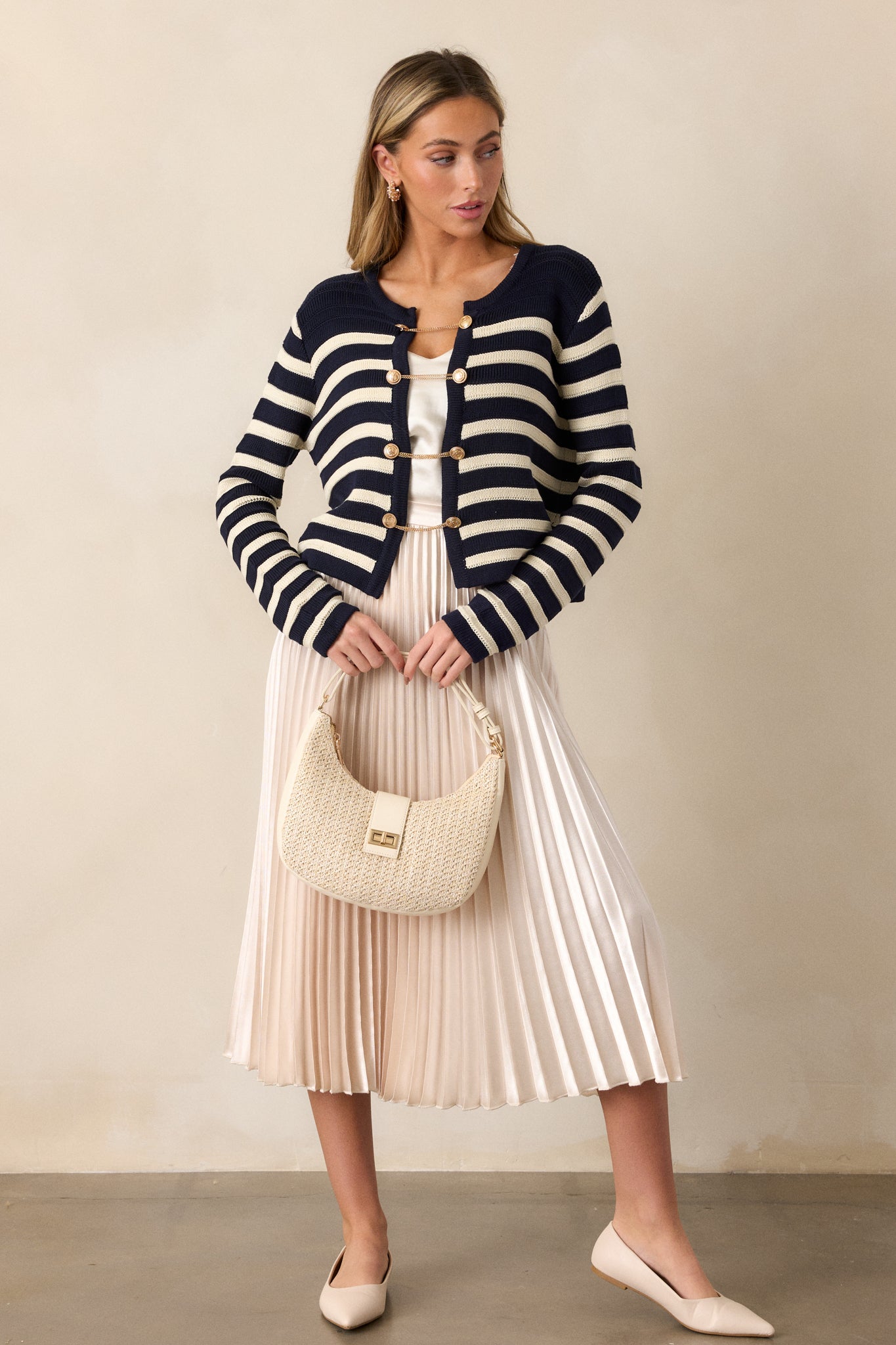 Front view of the cardigan, showing the rounded neckline, functional gold button and chain front, and navy and white stripe design.