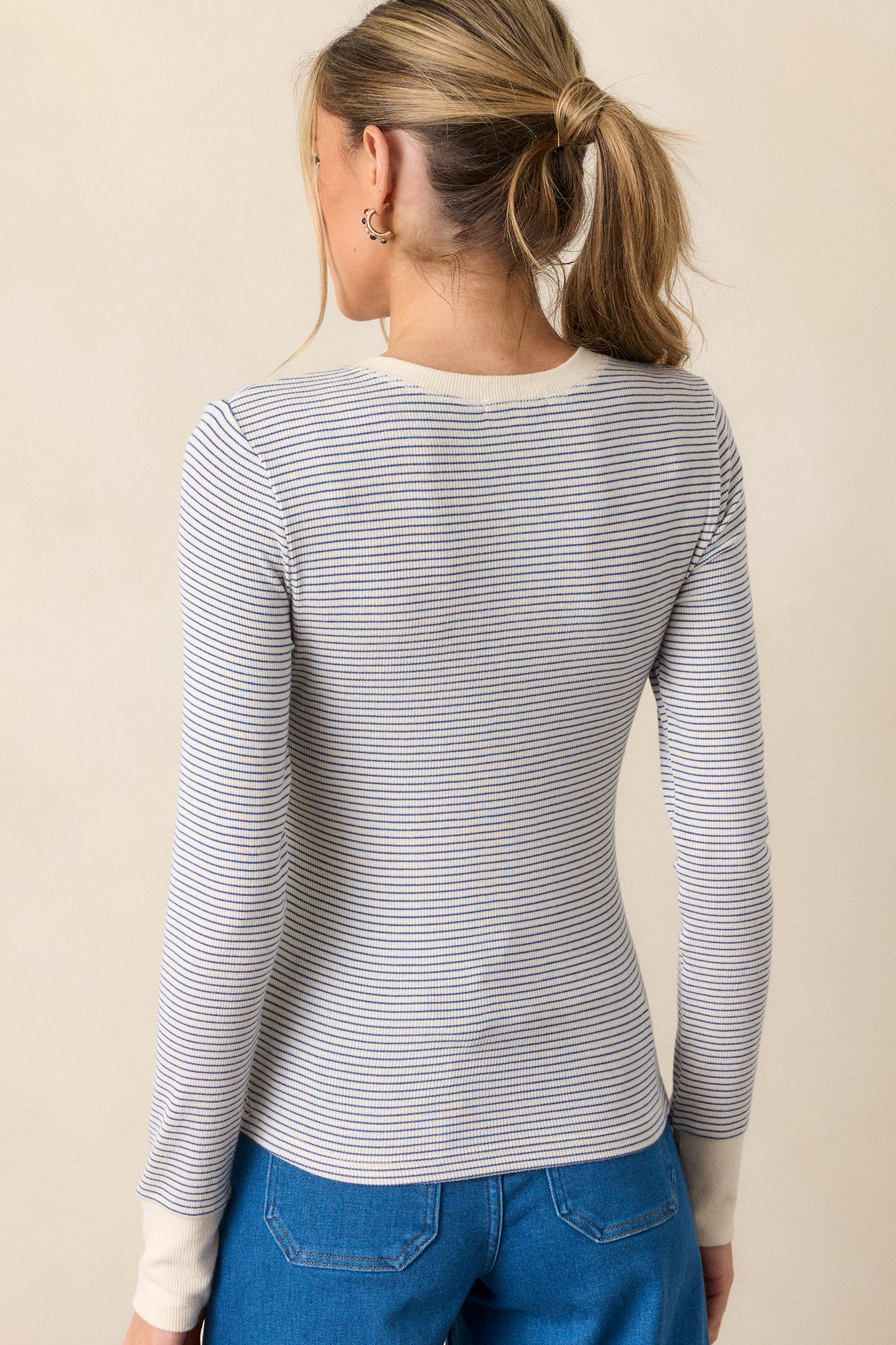 Back view of the blue top, showing the fitted design and consistent blue and ivory stripe pattern throughout the long sleeves and torso.