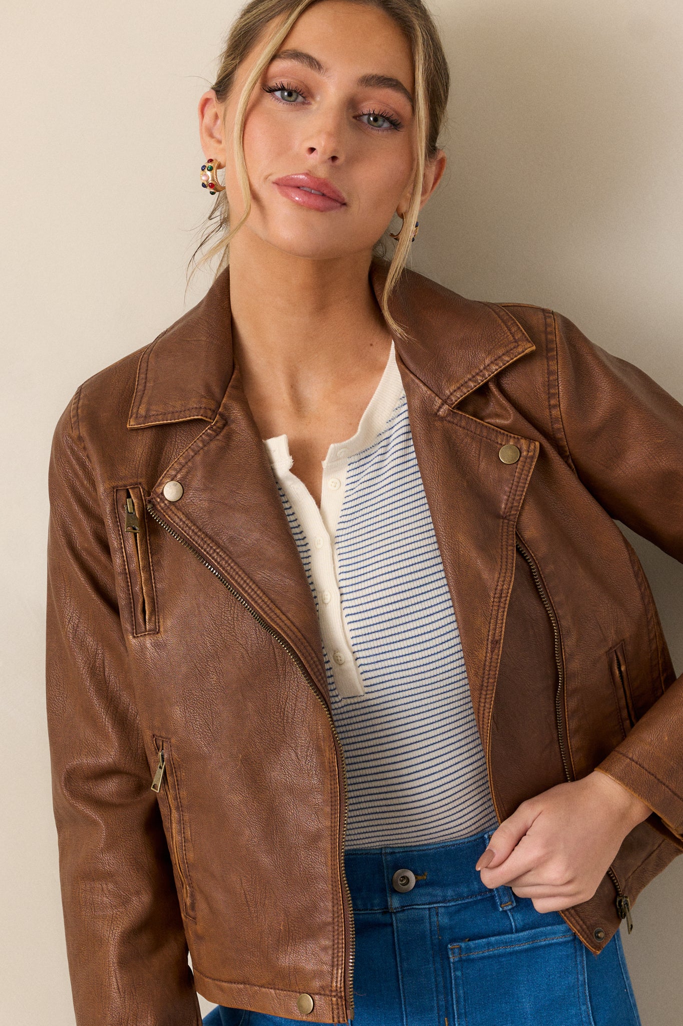 Front angled view of a jacket featuring washed gold hardware, a collar neckline with snap buttons, a front functional zipper, three functional zipper pockets, and slits on the sleeves with zipper closures.