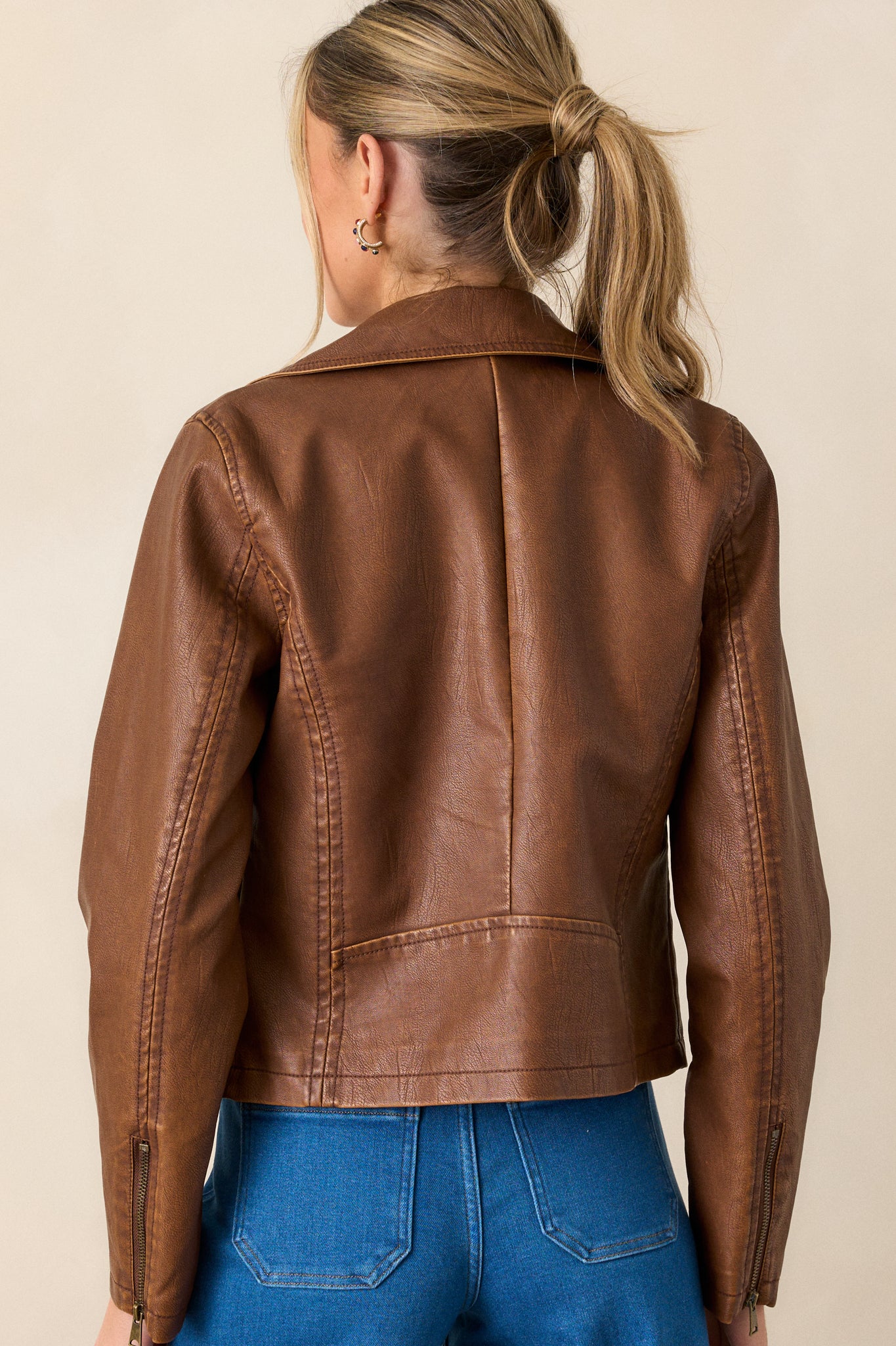 Back view of a jacket highlighting the overall fit, collar neckline, and slits on the sleeves with zipper closures.