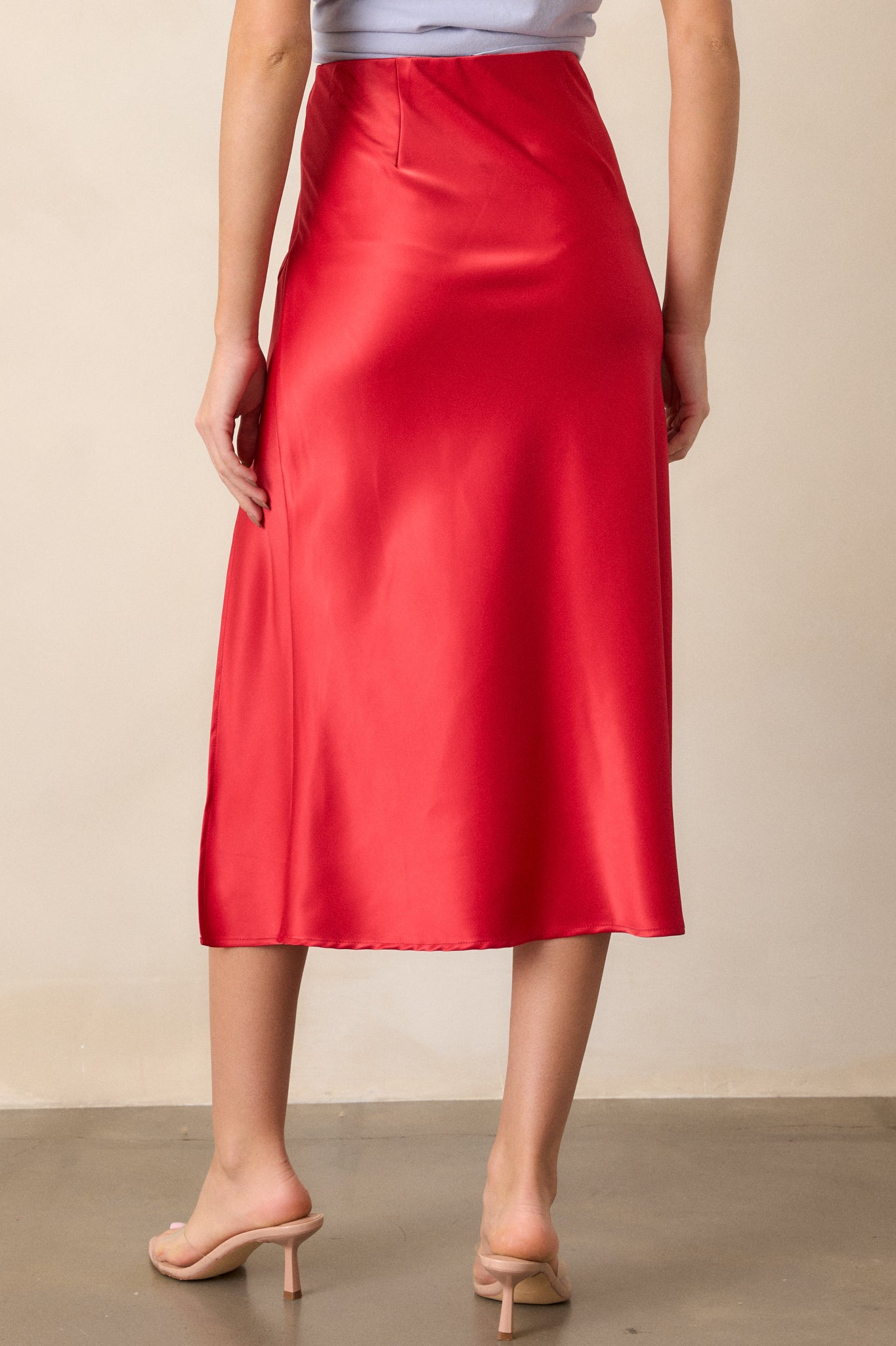 Back view of the red satin skirt, emphasizing the high waisted design and the clean, satin finish from behind.