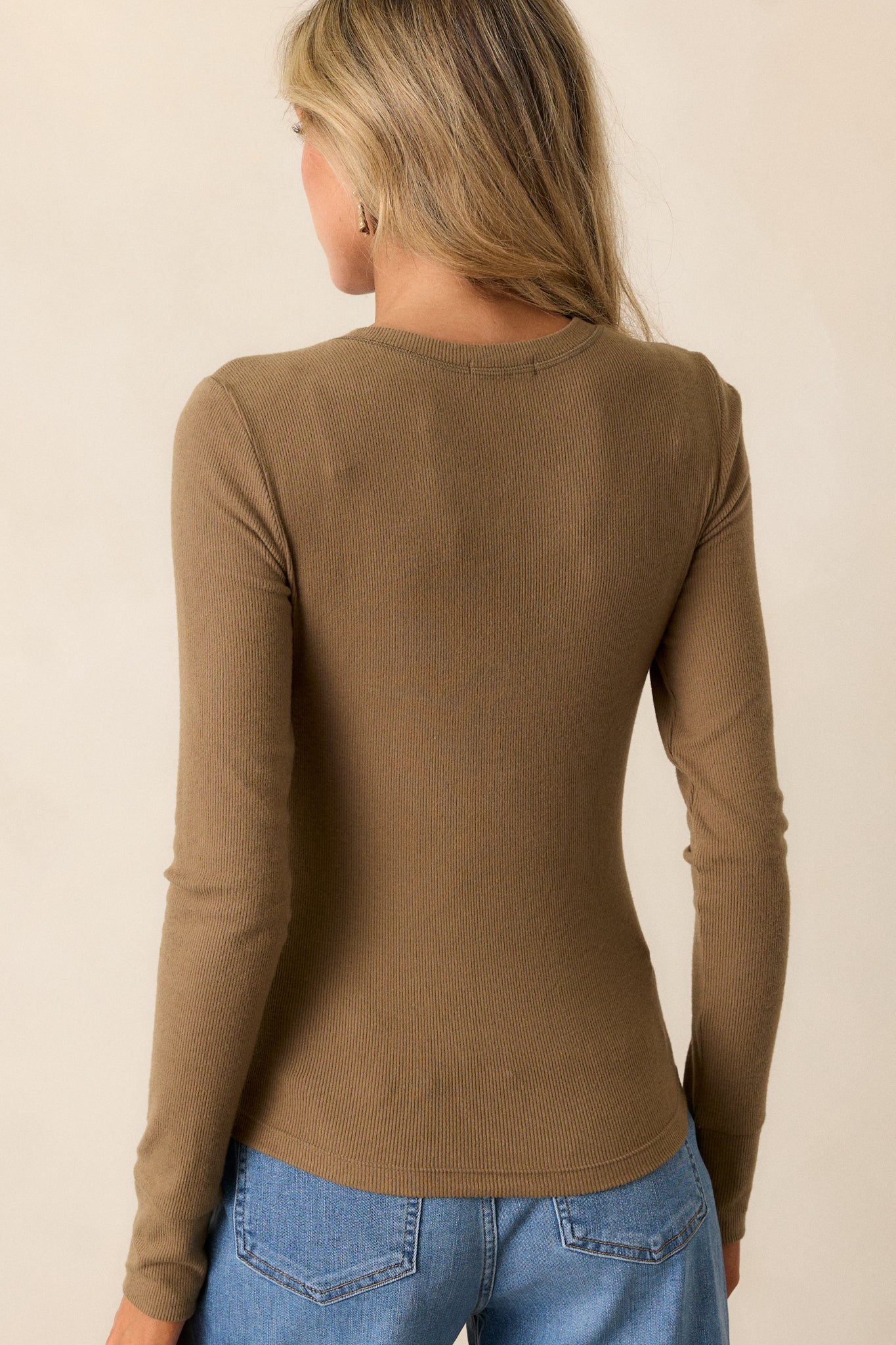 Back view of the fitted top, showing the ribbed detailing and contouring of the fabric across the back and long sleeves.