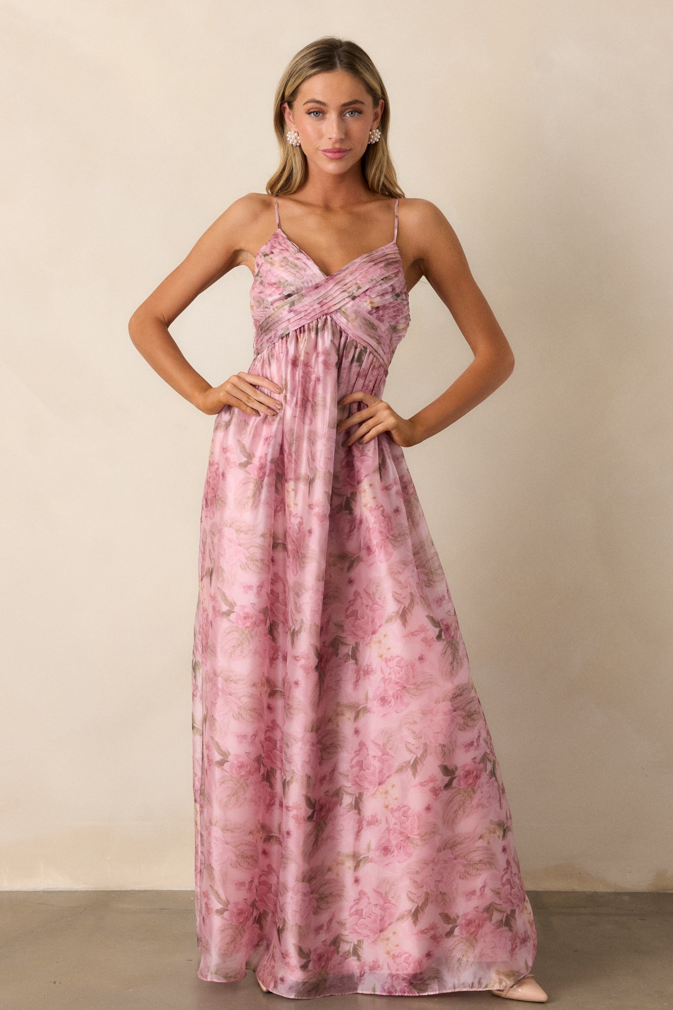 This pink dress features a v- neckline, empire waist, cross pleated detailing on the top, flowing skirt, an elegant floral design throughout, and spaghetti straps.