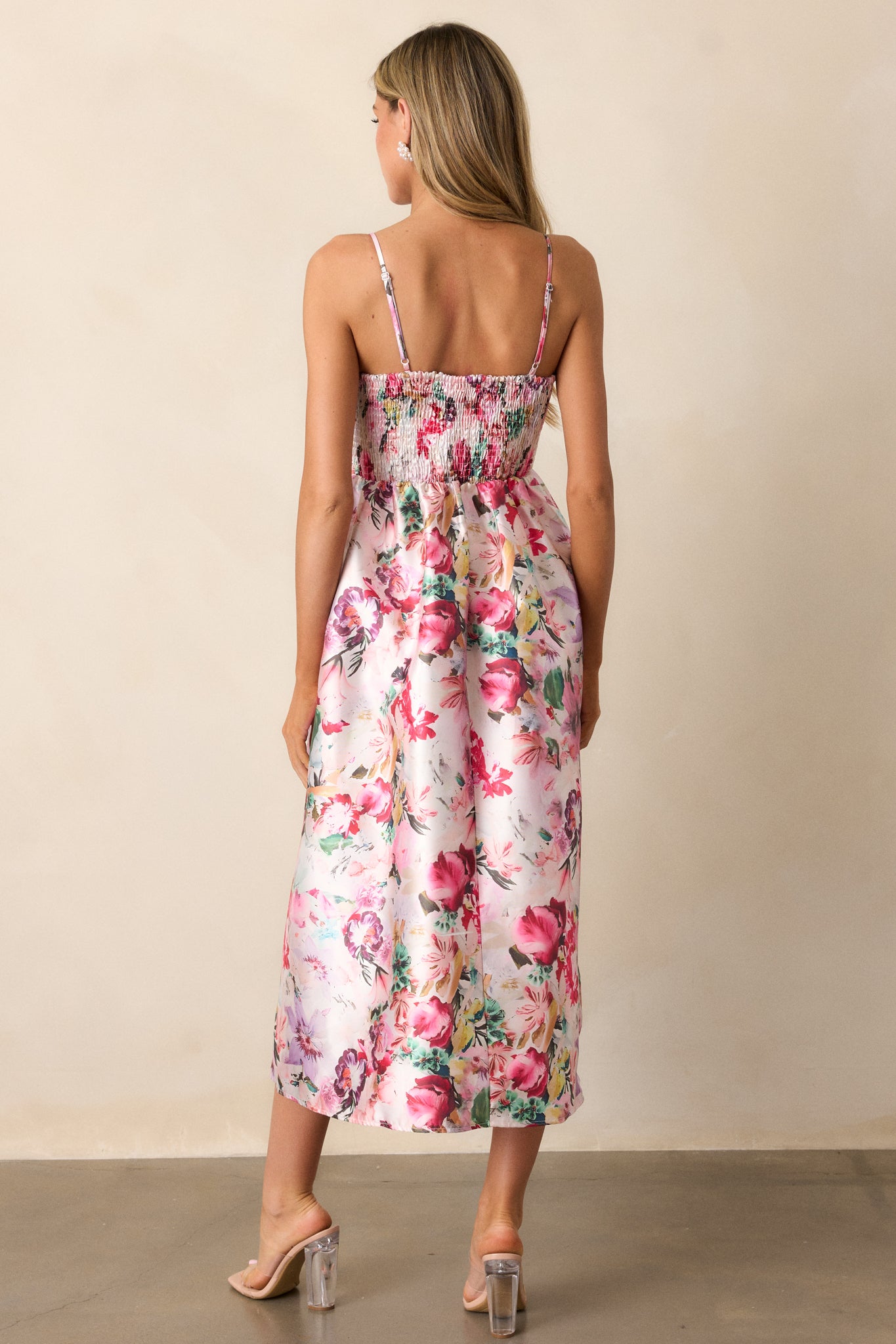 View of the back of the dress, featuring the smocked back, the discrete zipper, and the continuation of the floral print down to the hem.