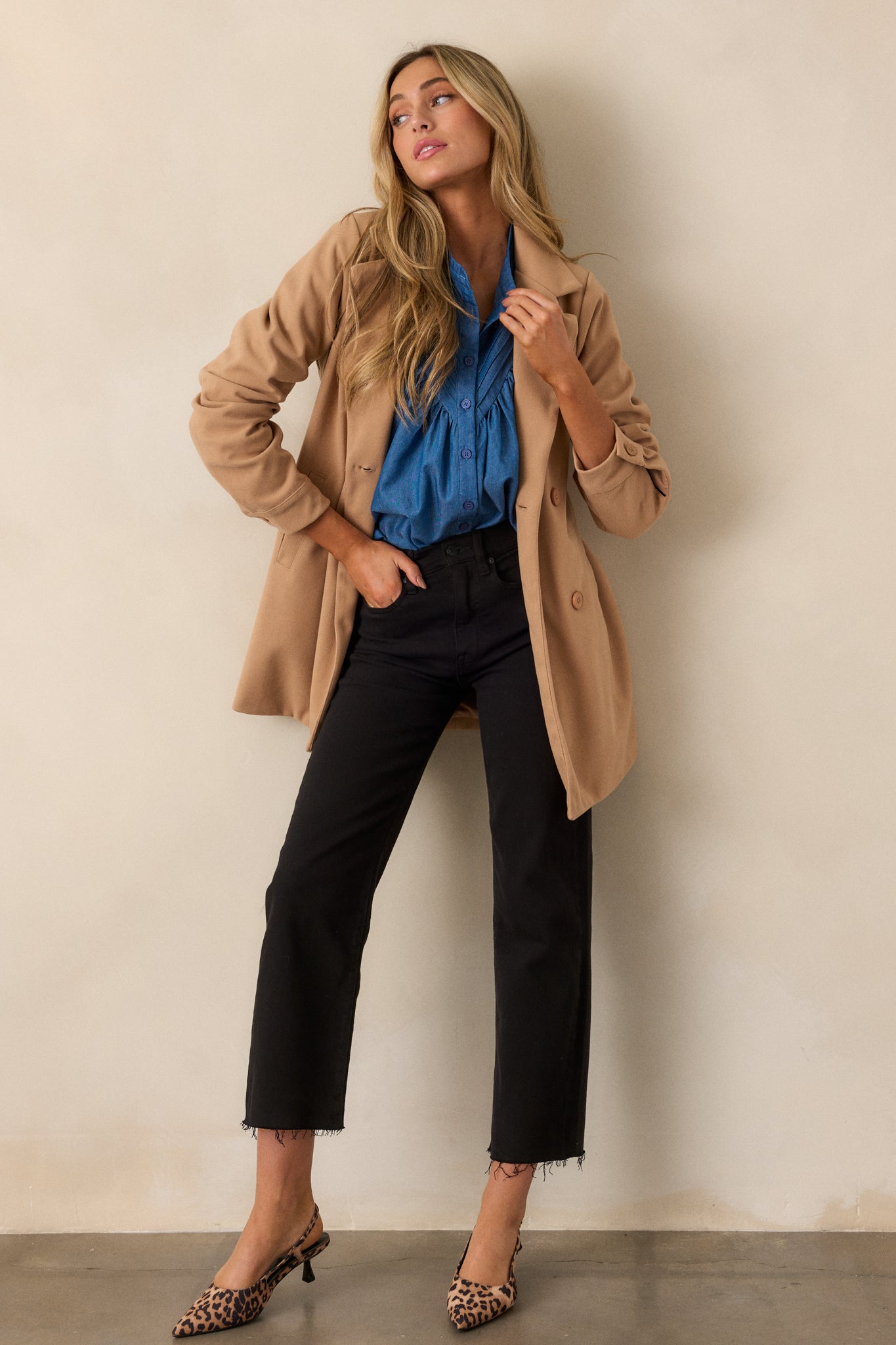  A full view of the camel coat featuring a collared neckline with notched lapels, a functional double-breasted button front, and long sleeves.