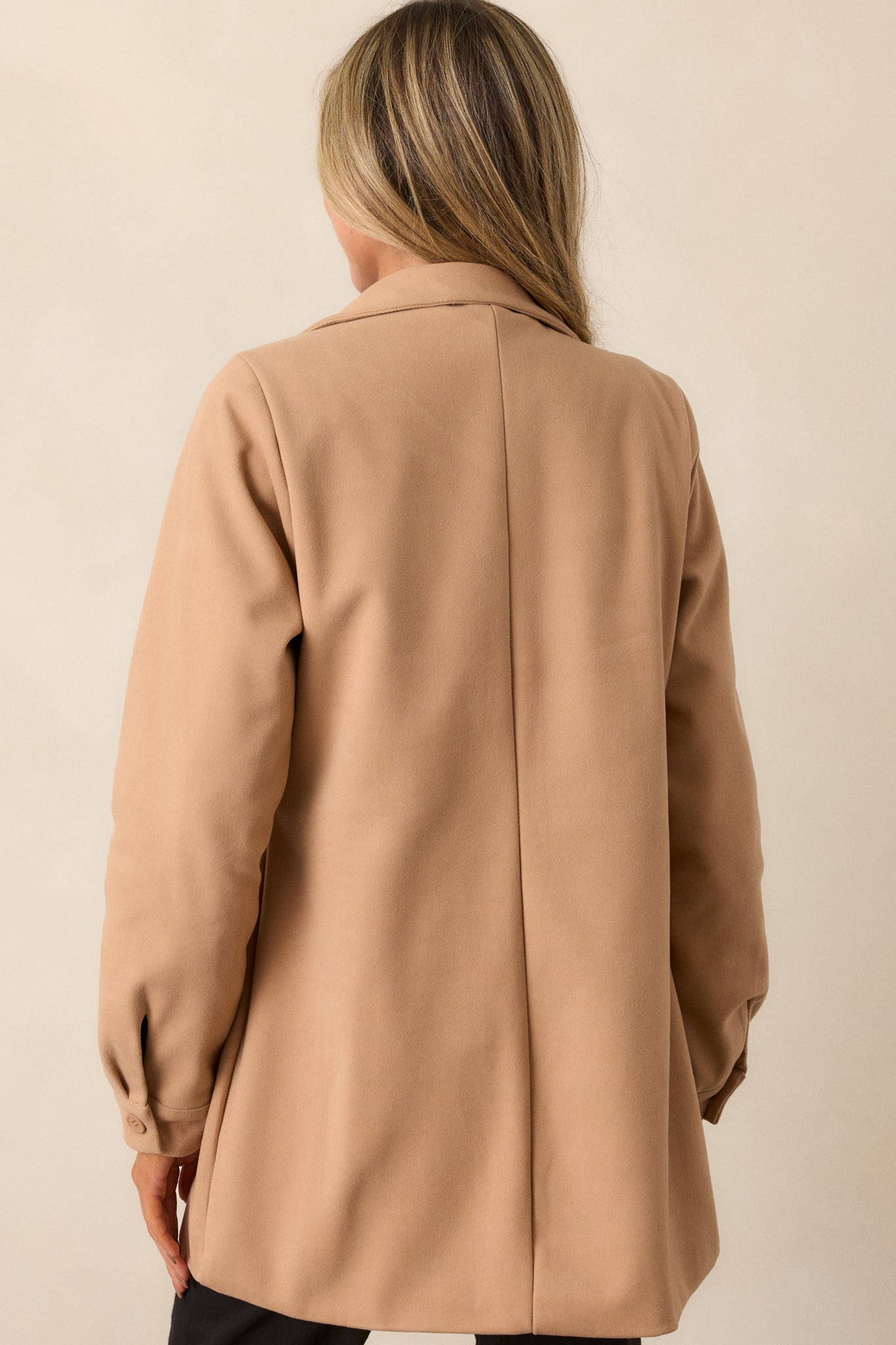 A back view of the coat, showing the long sleeves and the coat's structured fit with a seamless flow down to the hem.