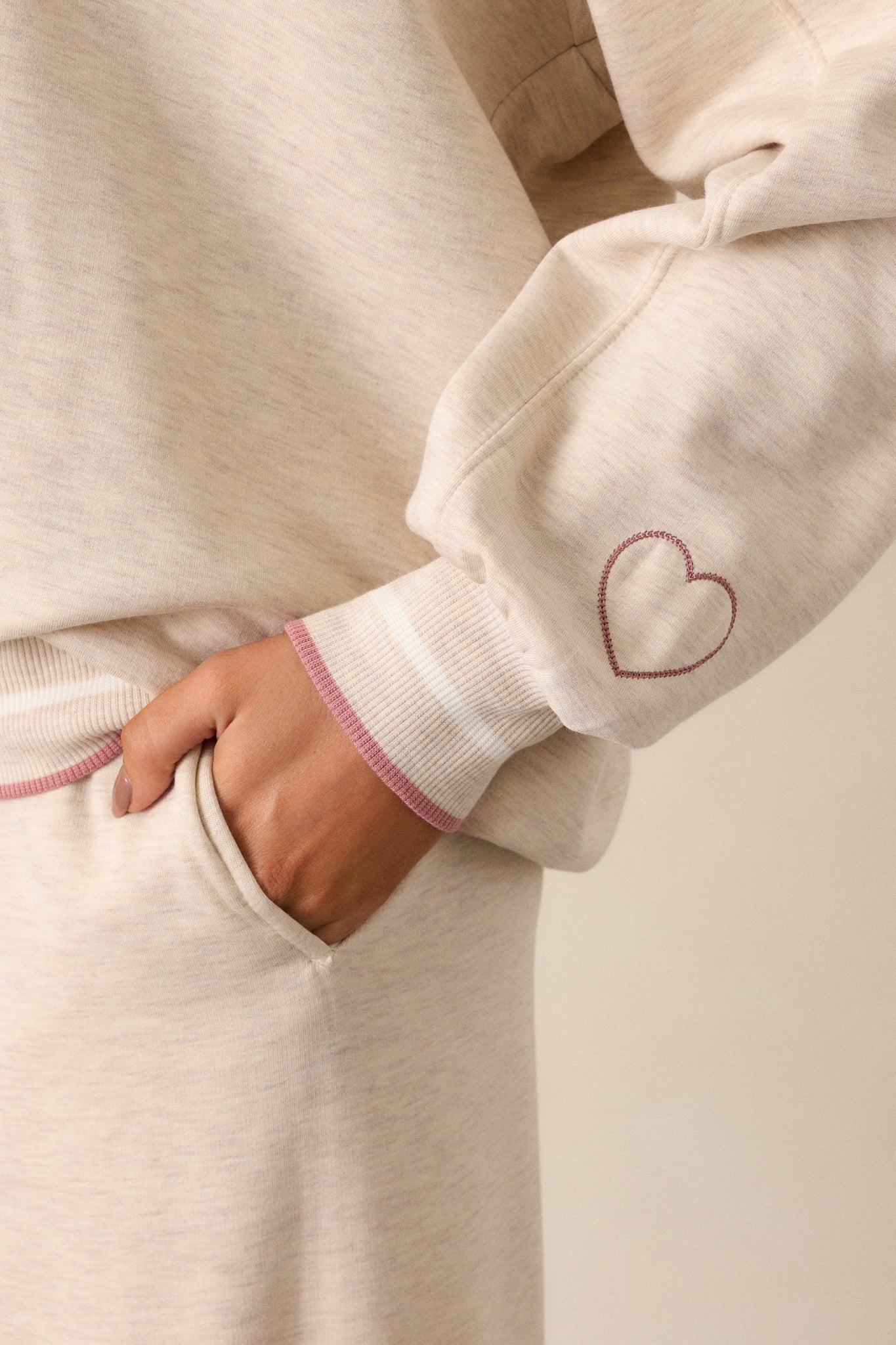 A close-up view of the long sleeves and ribbed cuffs of the oatmeal sweatshirt, showing the relaxed fit and pink trim detailing.