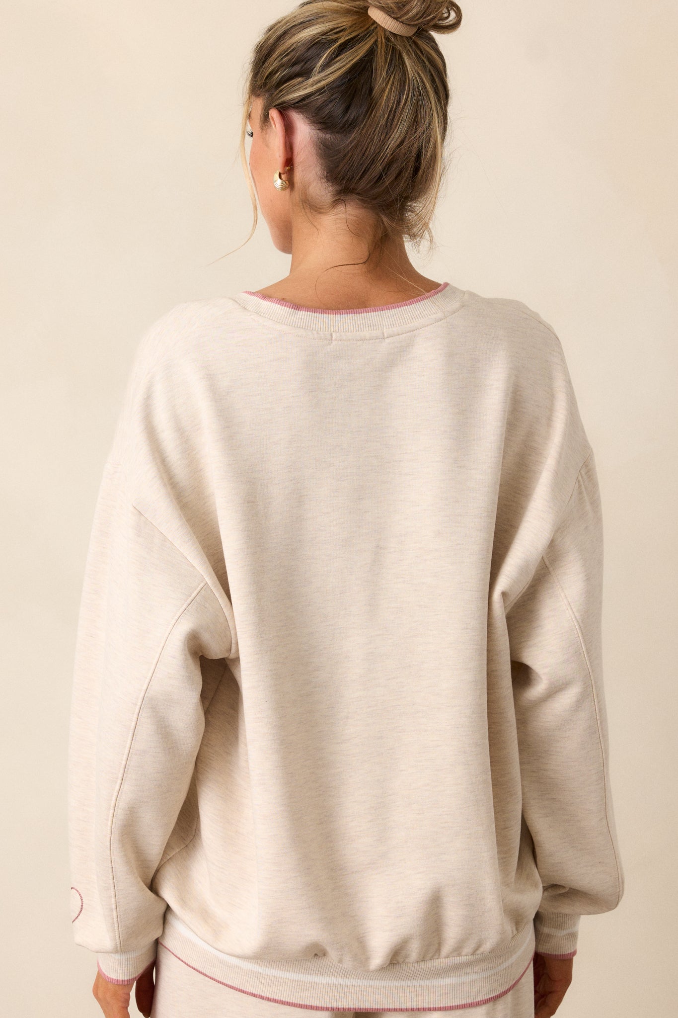 A back view of the oatmeal sweatshirt, showing the relaxed fit, ribbed bottom hemline, and long sleeves with ribbed cuffs.