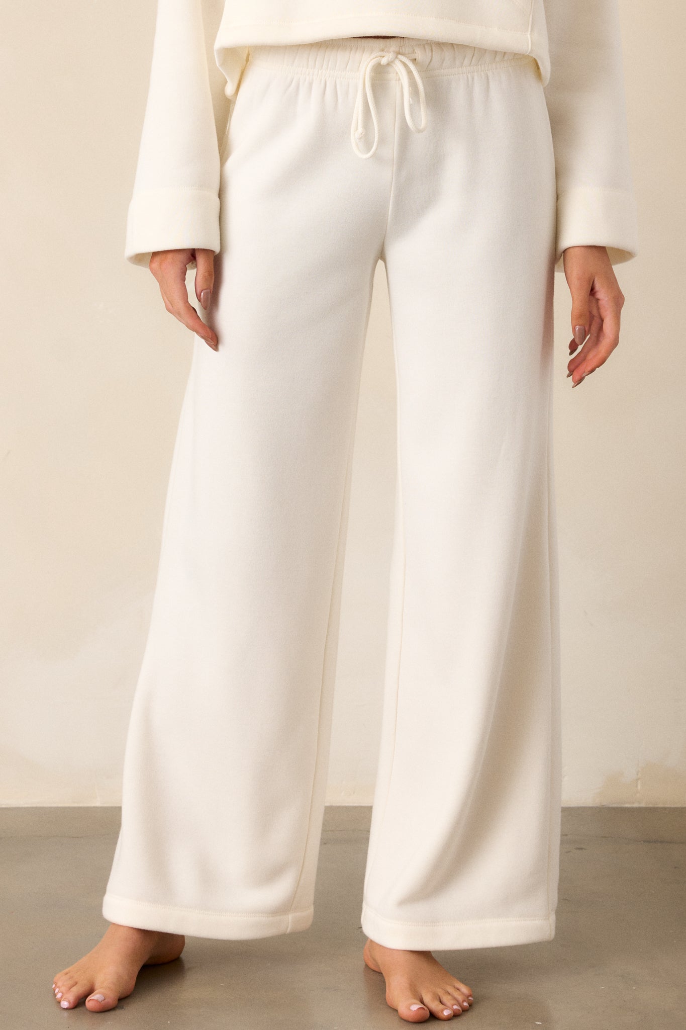 Close-up of the elastic waistband and adjustable drawstring of the ivory sweatpants, showing their functional design.