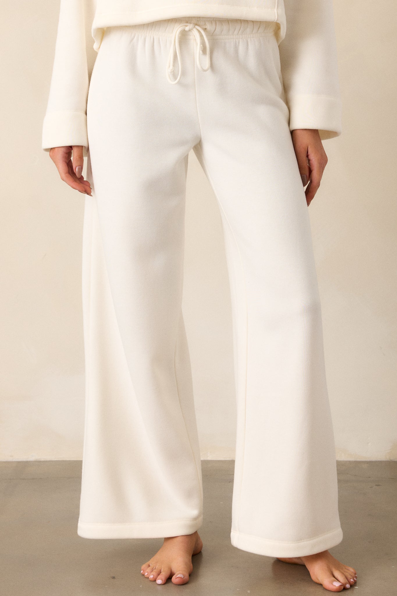 A cropped view of the wide-leg fit, focusing on the flowing, loose cut of the ivory fabric.