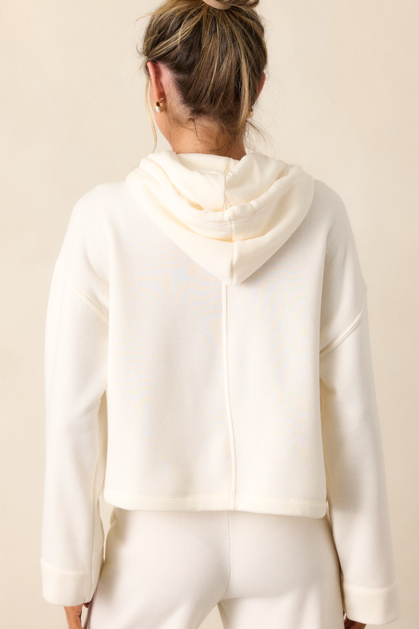 Back view of the ivory sweatshirt, showing the relaxed fit of the hood and loose sleeves from behind.