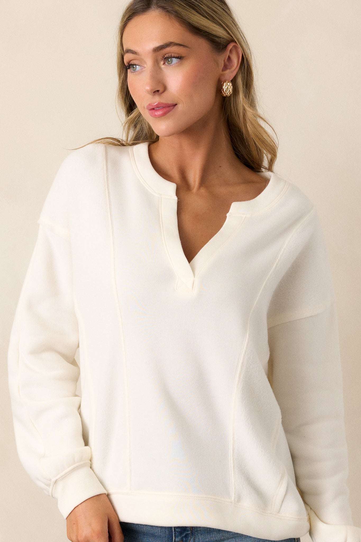 Cropped image of the upper half of the sweatshirt, focusing on the split neckline and unique reverse paneling details.