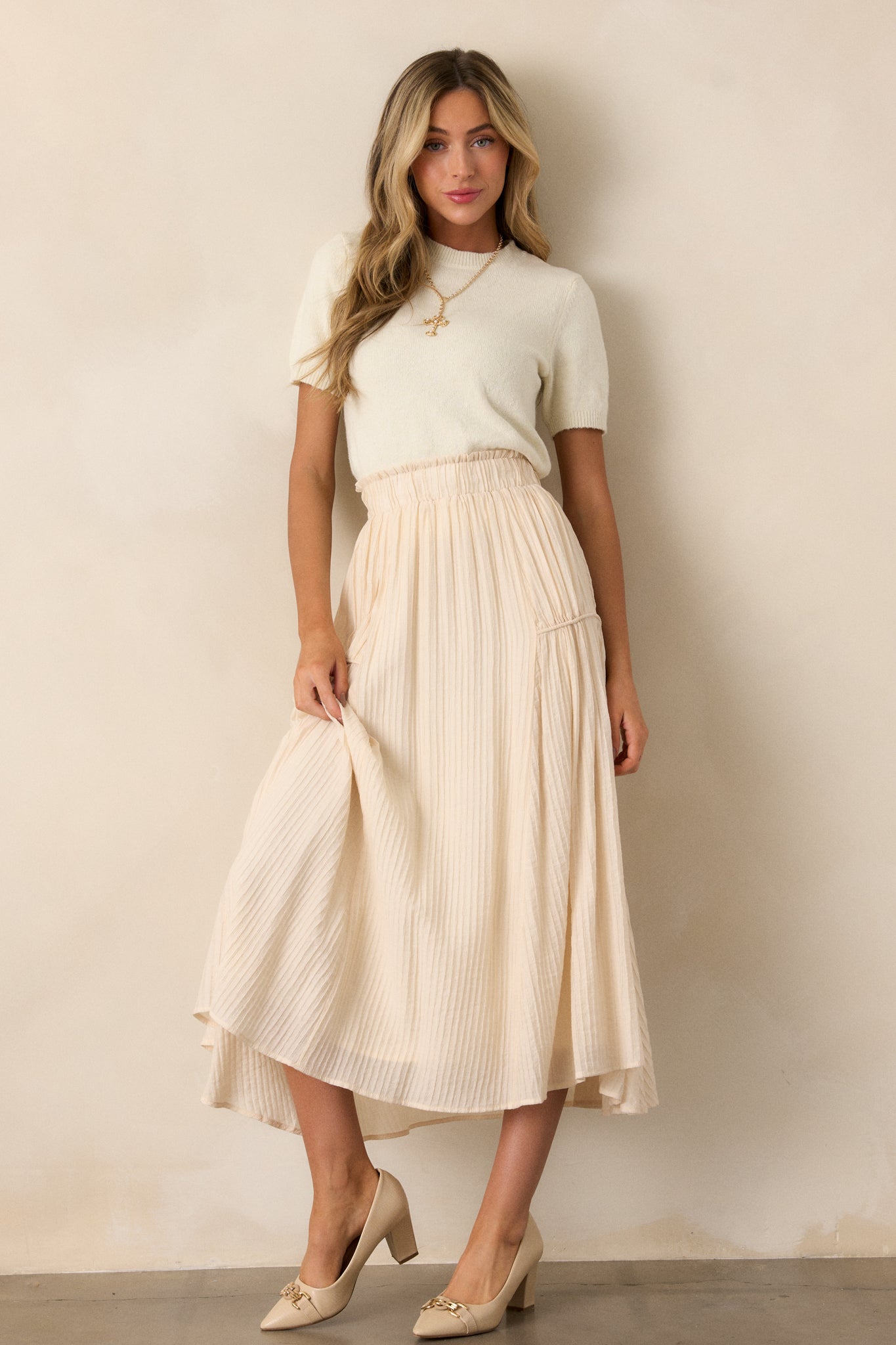 This beige maxi skirt features a high waist design, an elastic waistband, a ribbed texture, and a flowing silhouette.