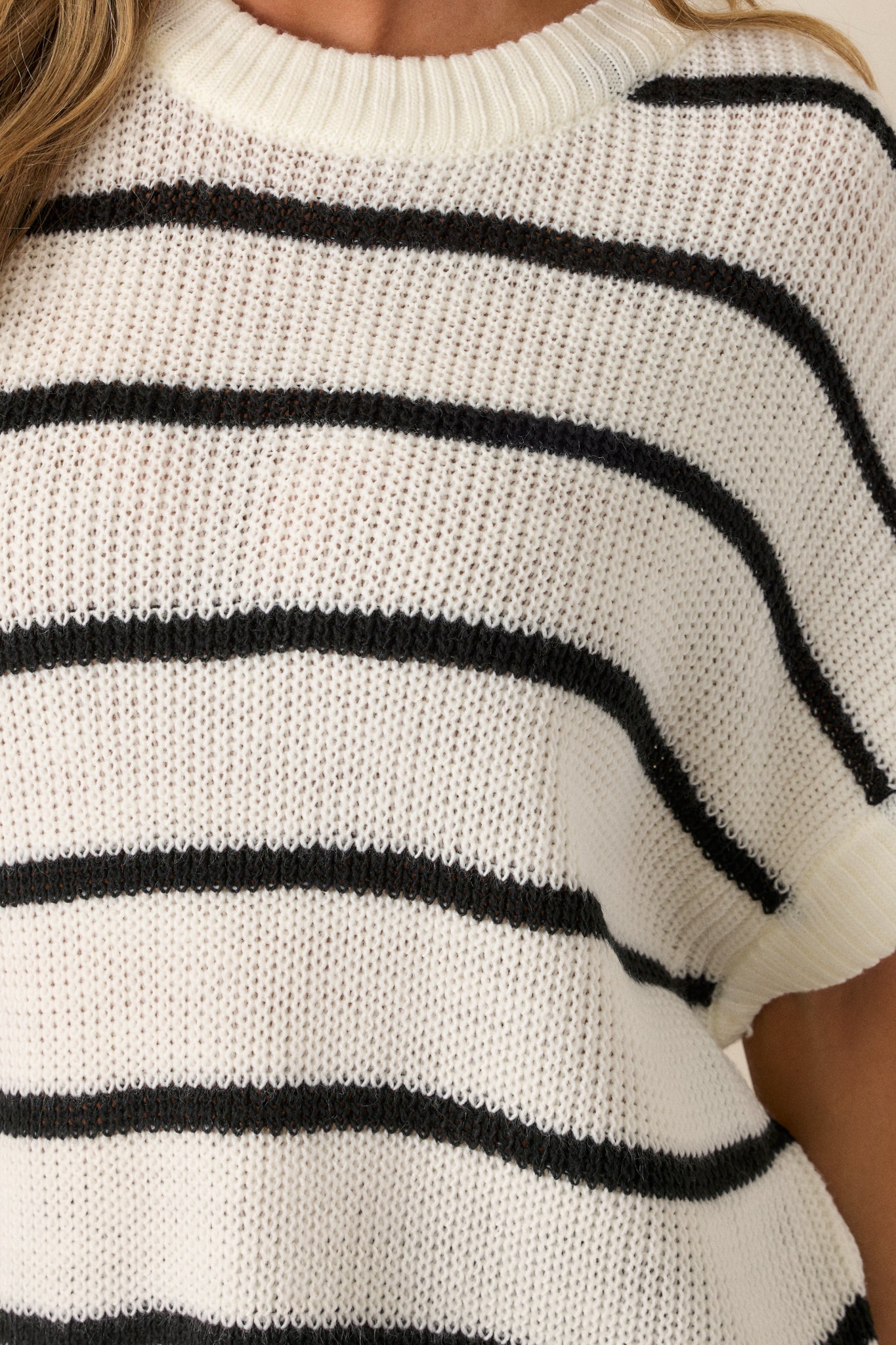 A detailed close-up of the top's ribbed neckline and the soft, relaxed fabric of the sweater. The stripes can be seen clearly, along with the texture of the ribbed bottom hem and short sleeves.