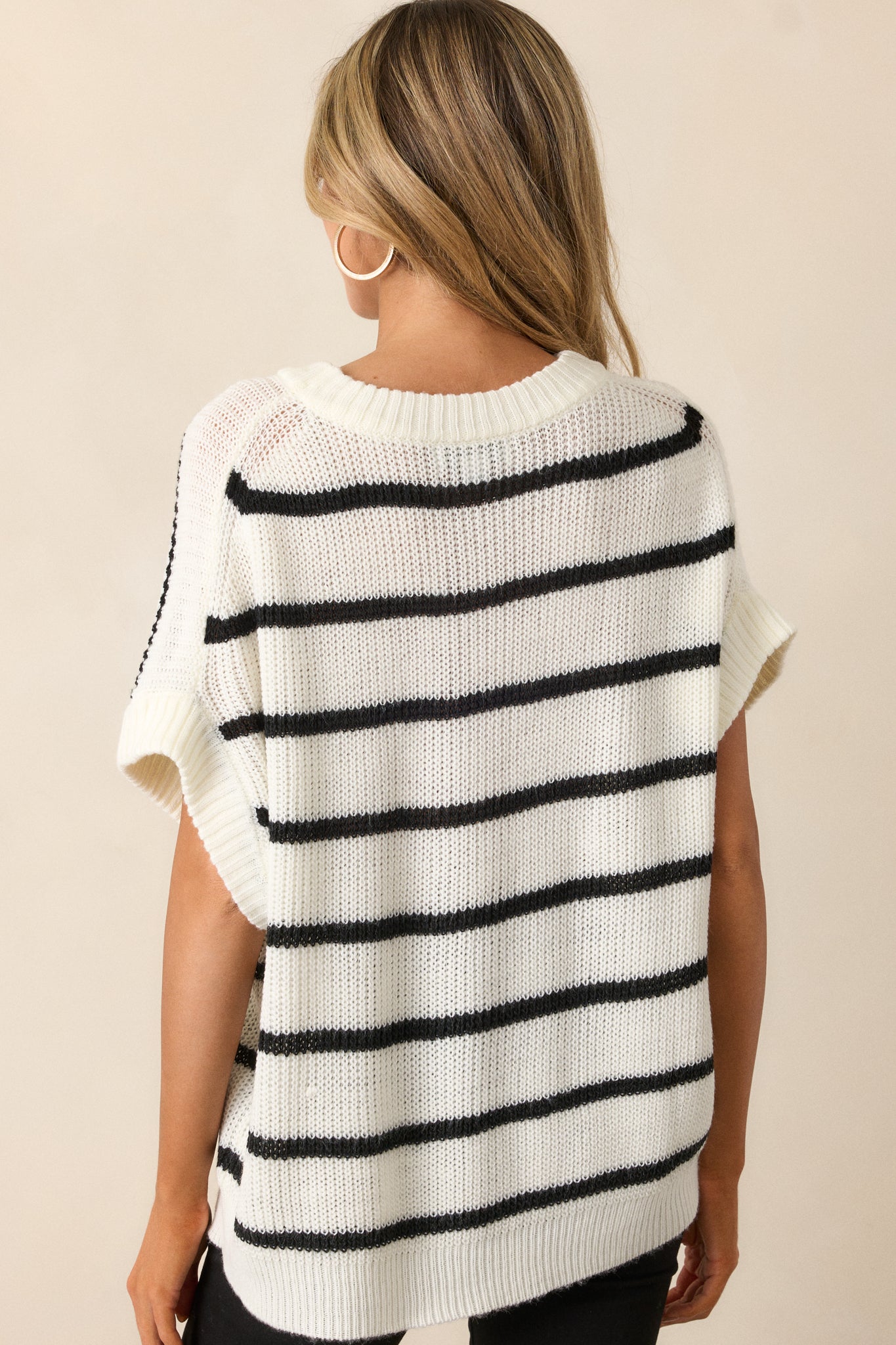 A back view of the white sweater top, showing the relaxed fit and short oversized sleeves. The striped pattern continues across the back, and the ribbed bottom hem is visible at the waist.