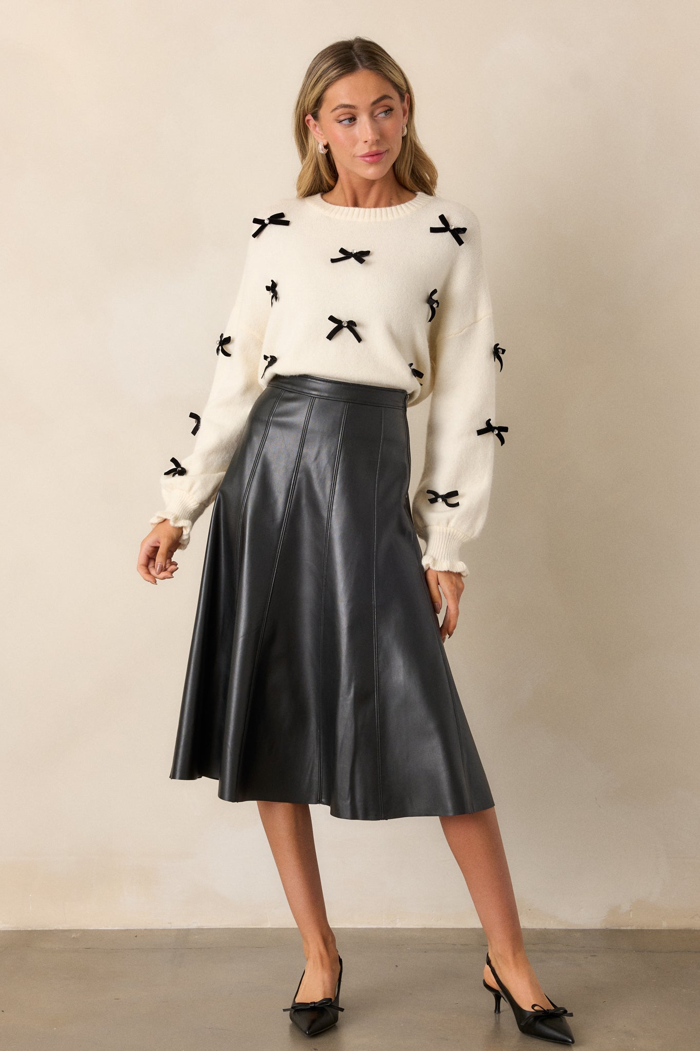 Front view of the black faux leather midi skirt, showcasing its sleek flare design and vertical seams.