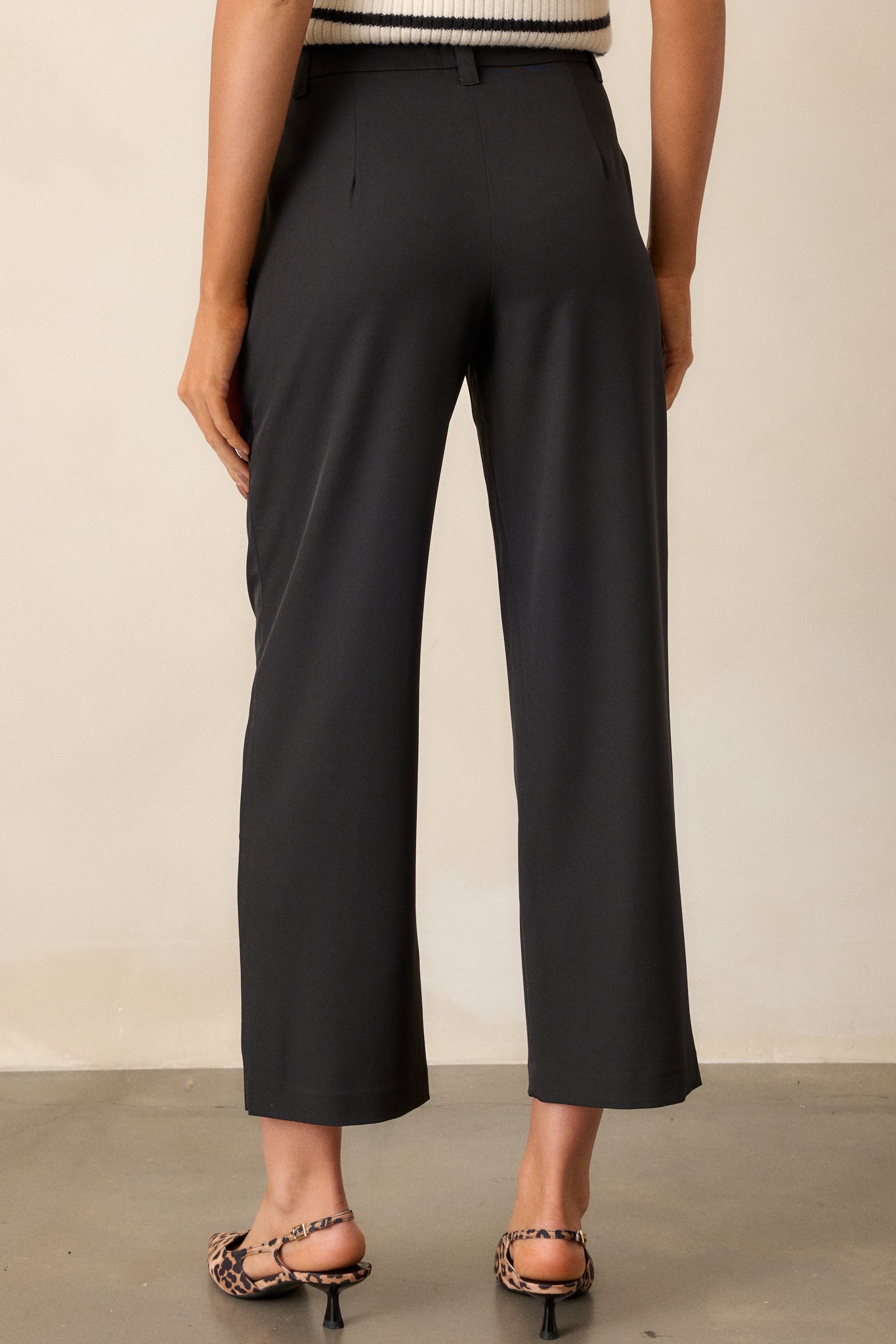 Back view of black straight leg pants with functional belt loops, styled with a black top and heels.