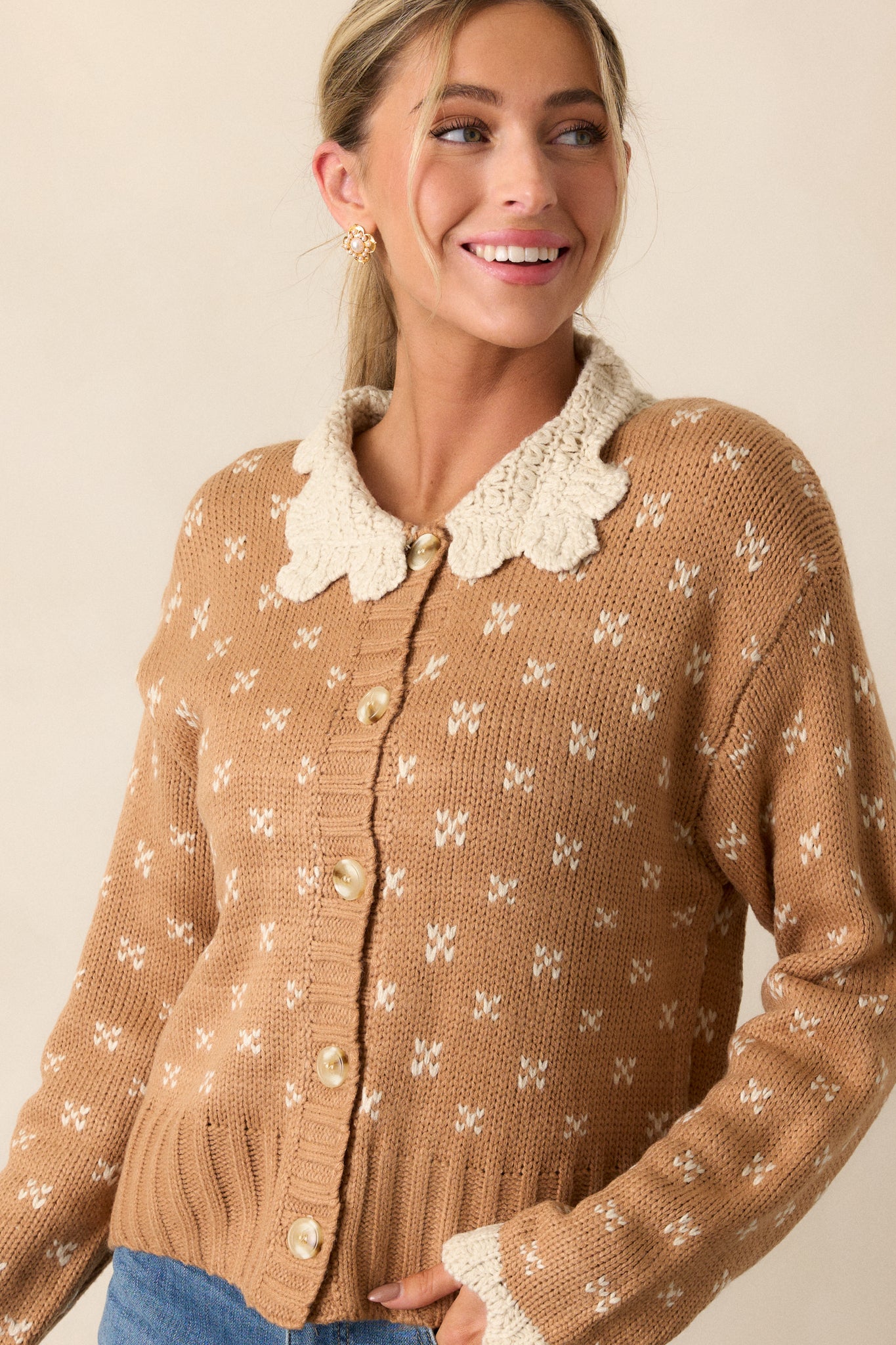 Front view of a honey cardigan featuring an ivory crochet peter pan collared neckline, functional button front, ditsy heart cluster print, and long sleeves with ivory crochet wrist cuffs.