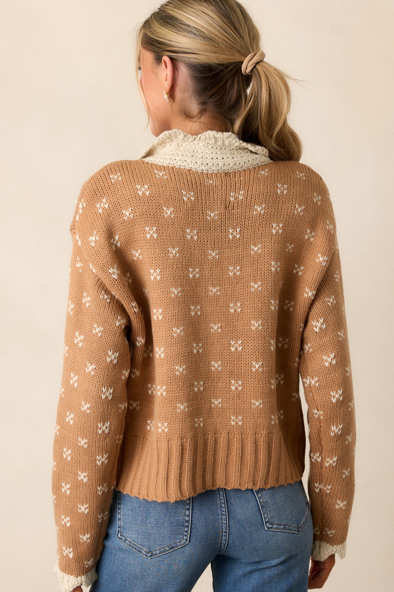 Back view of a honey cardigan featuring an ivory crochet peter pan collared neckline, functional button front, ditsy heart cluster print, and long sleeves with ivory crochet wrist cuffs.