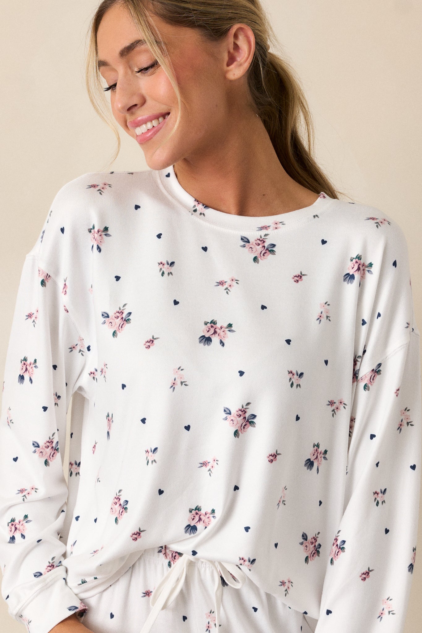 A cropped shot focusing on the long sleeves of the ivory top, showcasing the relaxed fit and the rosebud pattern. The crew neckline adds to the top’s casual yet stylish design.