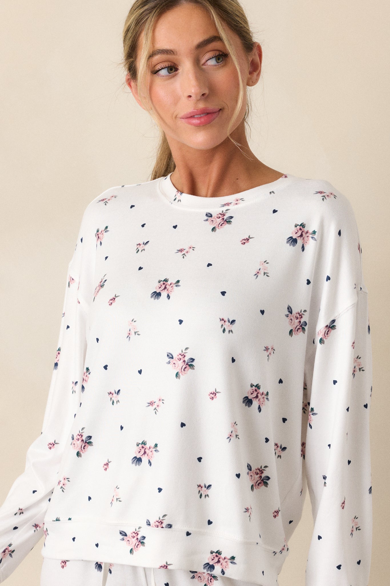 A front angled view of the ivory top, showcasing the soft fabric with the rosebud pattern. The top’s relaxed fit and long sleeves provide a comfortable, casual silhouette.