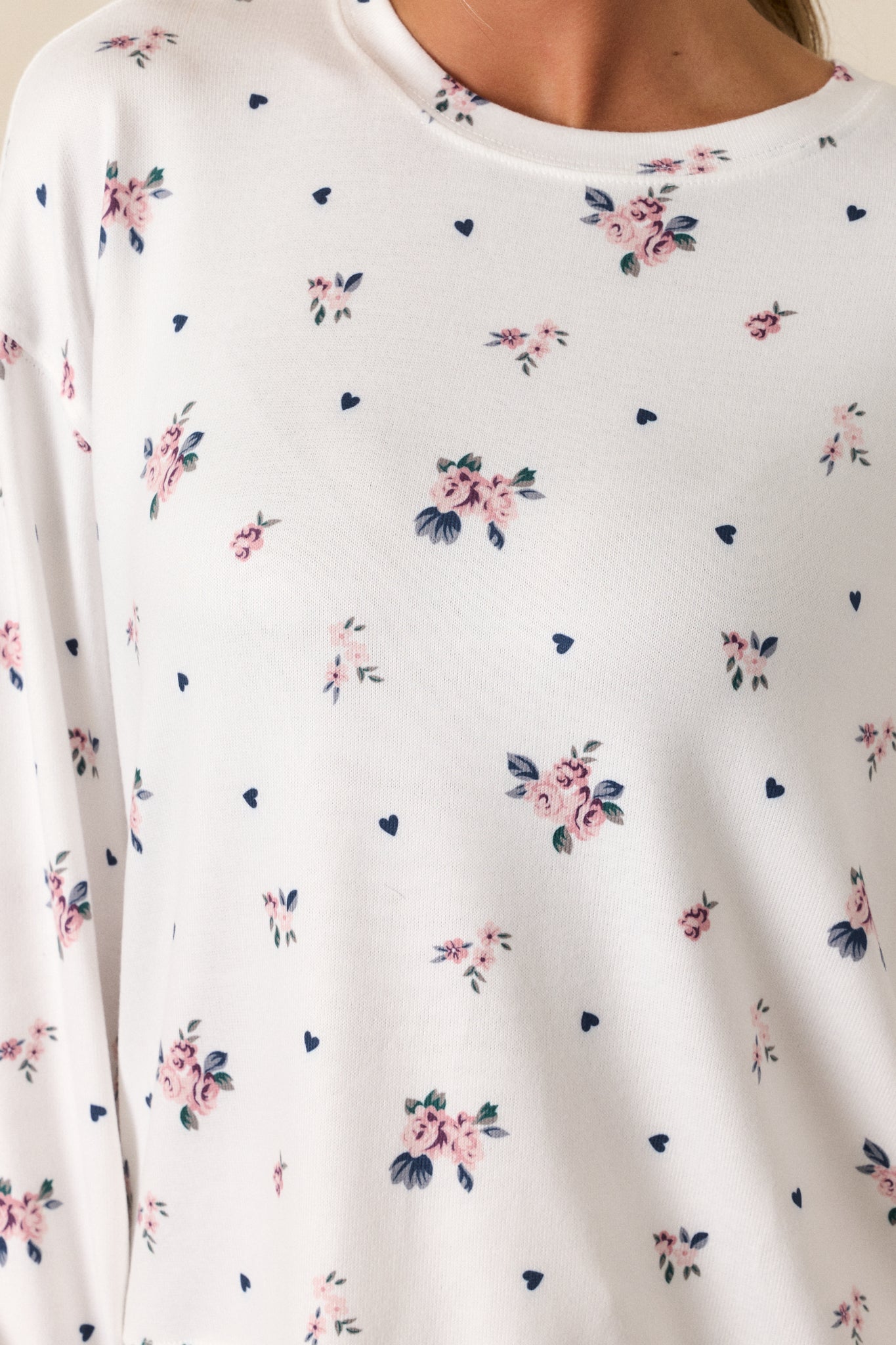 A detailed shot focusing on the rosebud pattern of the ivory top. The soft texture of the fabric and the relaxed fit are clearly visible, along with the subtle detailing around the neckline.