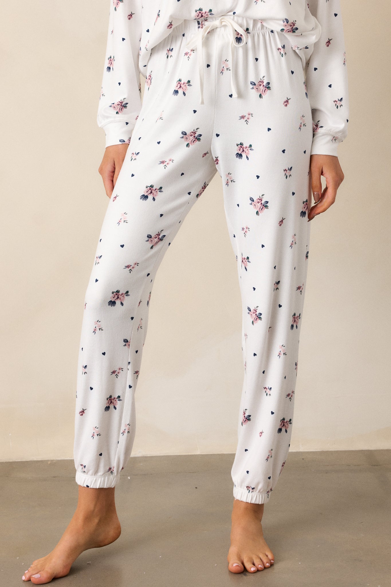 Another cropped shot highlighting the ivory joggers, showing their relaxed fit and high waist design. The rosebud pattern and elastic ankle cuffs complete the casual, stylish look.