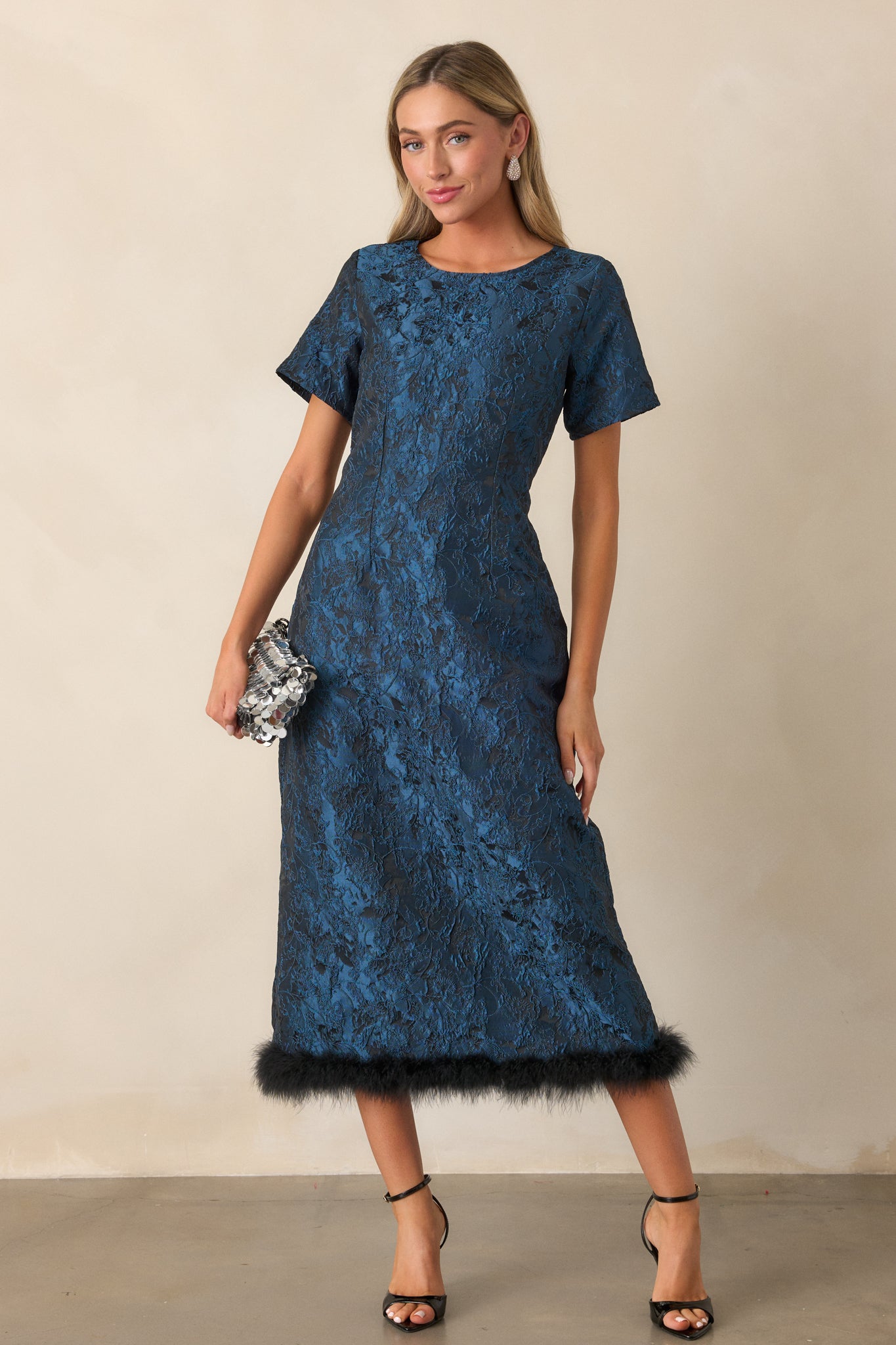 Front view of the dark teal midi dress featuring a round neckline, structured fit, short sleeves, and a faux fur hem that adds texture to the skirt.