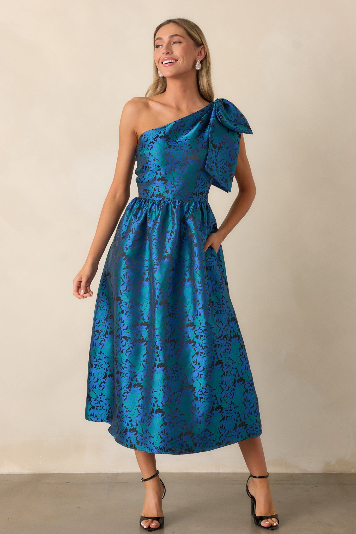 Full-length shot of the blue midi dress, focusing on the overall fit and flare design and highlighting the jacquard fabric's pattern as it flows down to the hem.