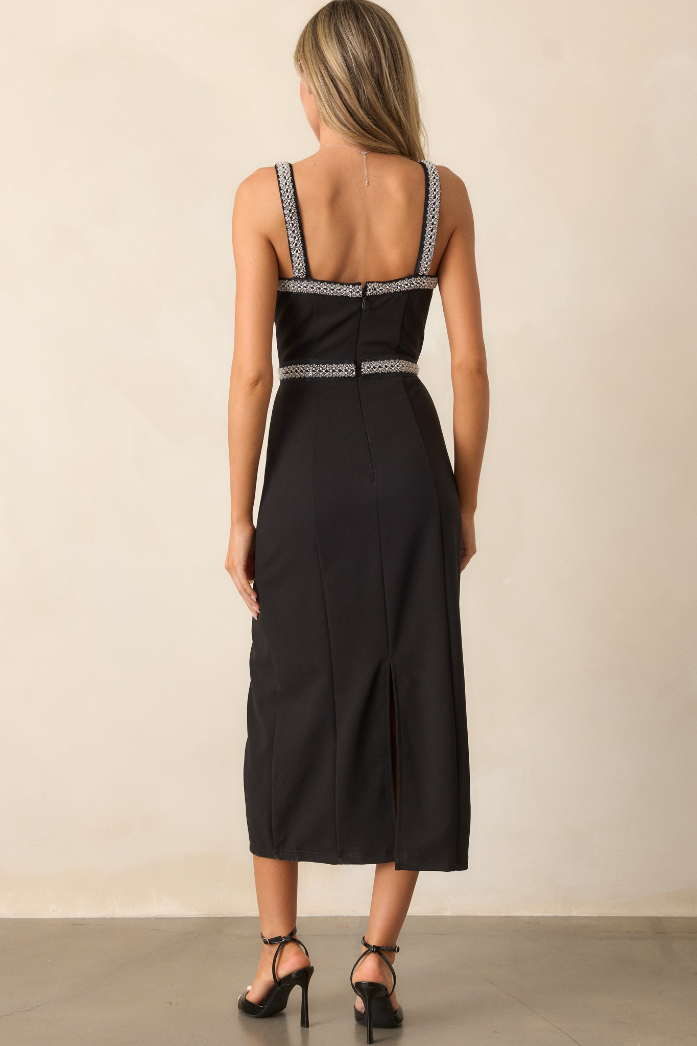 Full shot of the back of the black midi dress, focusing on the discrete zipper and the smooth fabric finish.