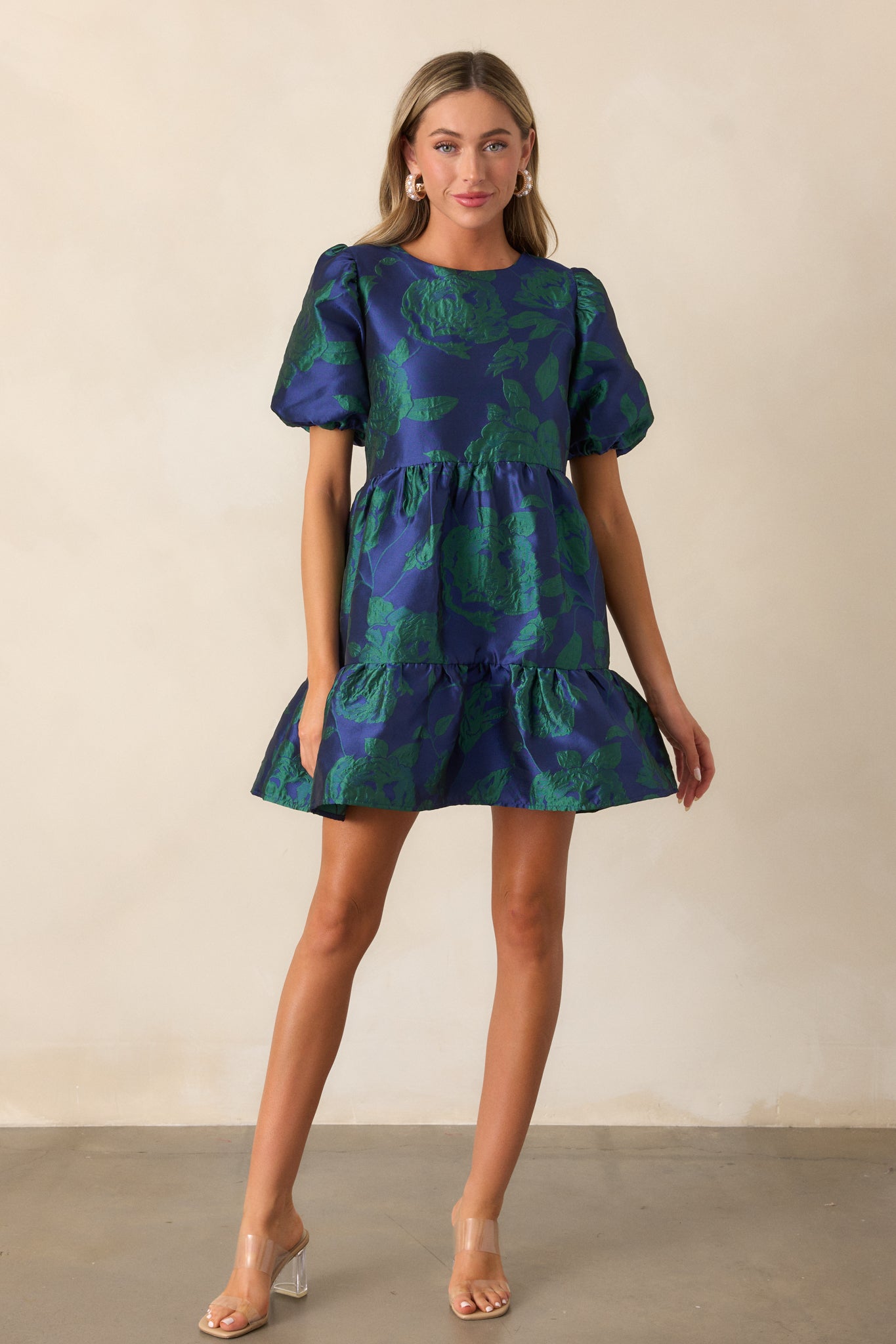 Chic midnight blue mini dress with a voluminous tiered skirt and delicate puff sleeves, perfectly showcasing its textured jacquard fabric and flattering silhouette with a round neckline.