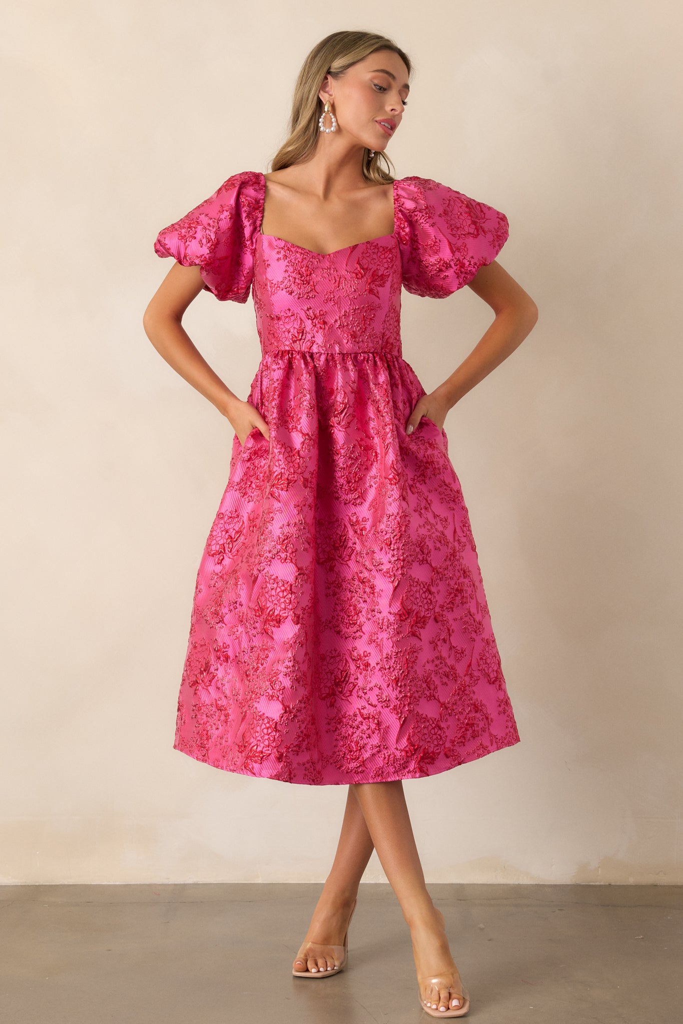 Another shot of the pink midi dress showcasing a sweetheart neckline, puff sleeves, and the fit and flare design with sparkle red detailing throughout.