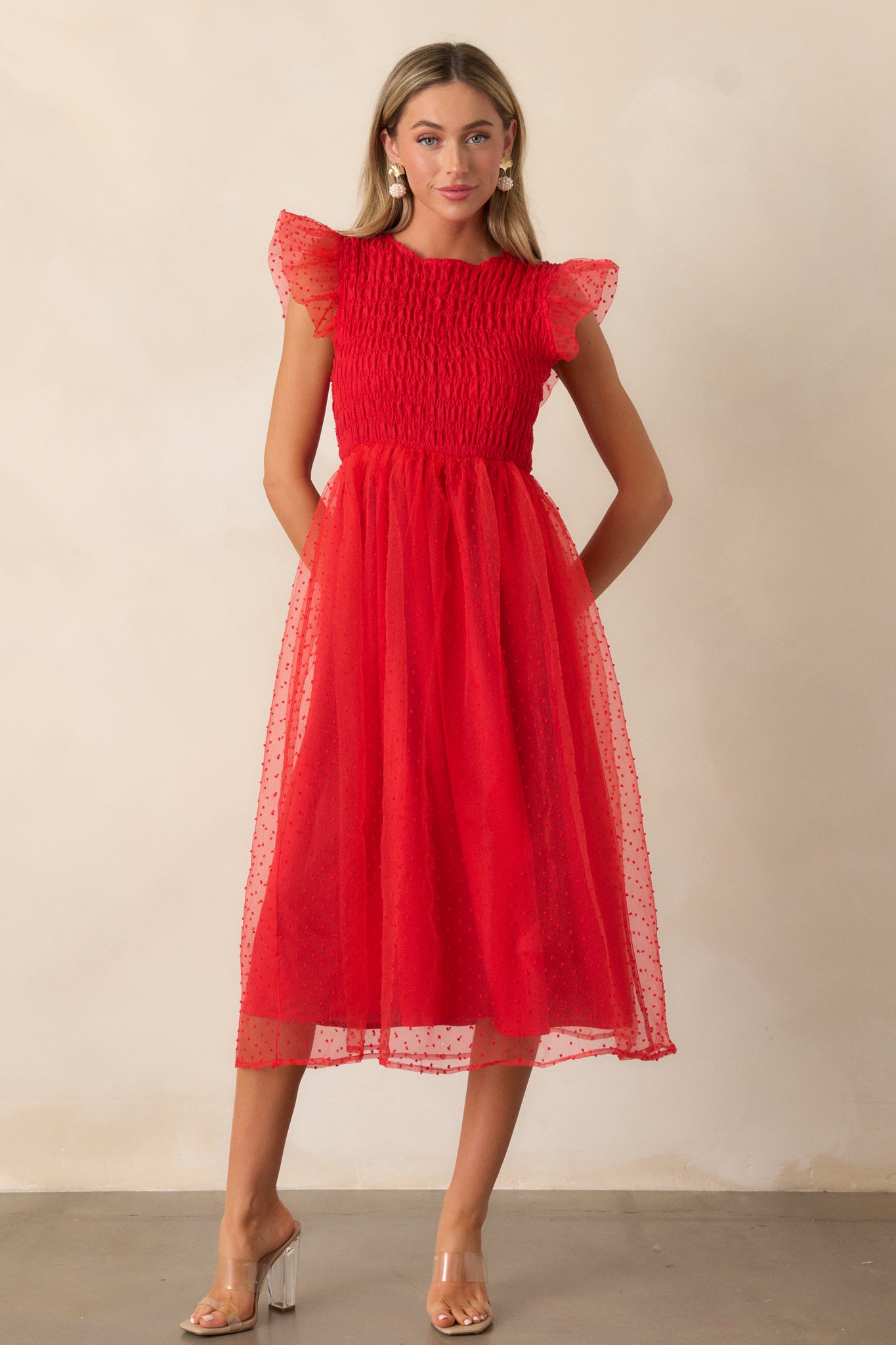 Front-facing shot of the dress, emphasizing the smocked bodice and flutter sleeves with the whimsical polka dot tulle overlay adding a playful, light feel to the look.