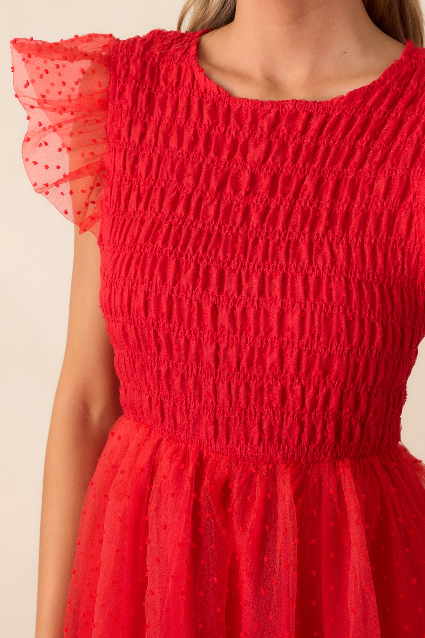 Close-up of the dress's smocked bodice with the polka dot tulle overlay, focusing on the intricate texture of the fabric and the delicate flutter sleeve detailing.