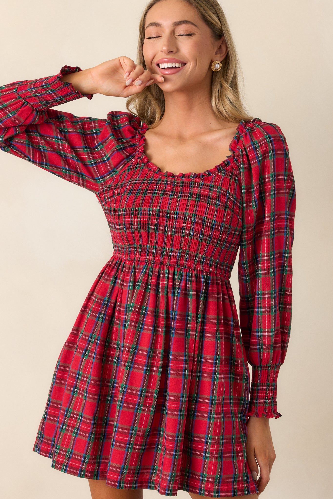 Cropped front view showing the smocked bodice and long sleeves with smocked cuffs, with the plaid print clearly visible.