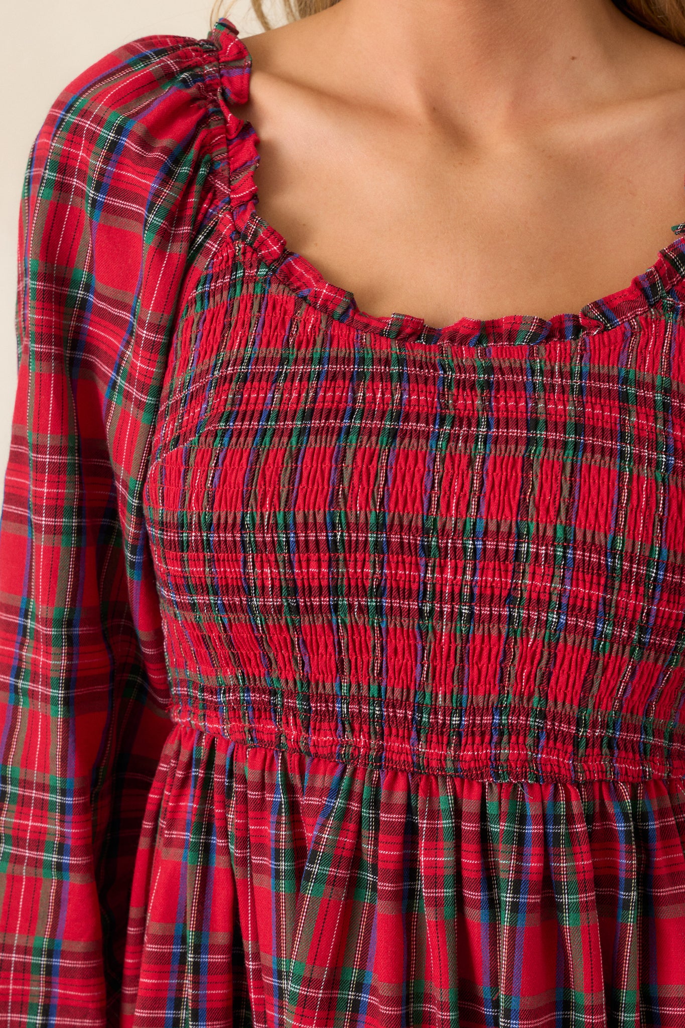 Close-up shot highlighting the scoop neckline with ruffle trim and the texture of the smocked bodice with the plaid print.