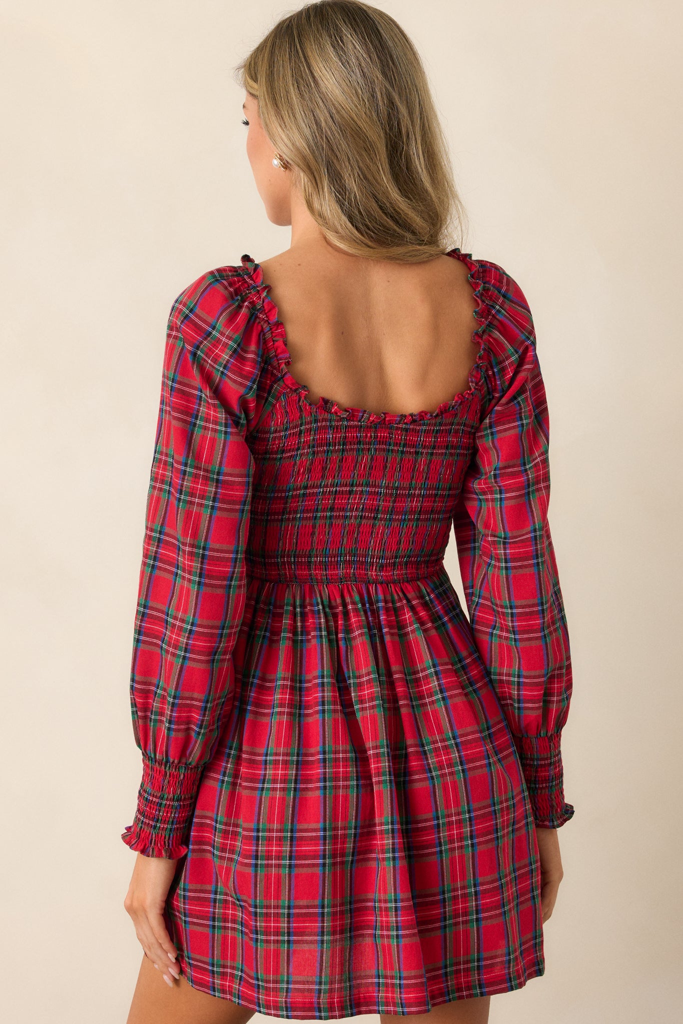 Back view of the red mini dress showing the smocked bodice and the length of the dress, with the fabric gently flowing from the fitted waist.