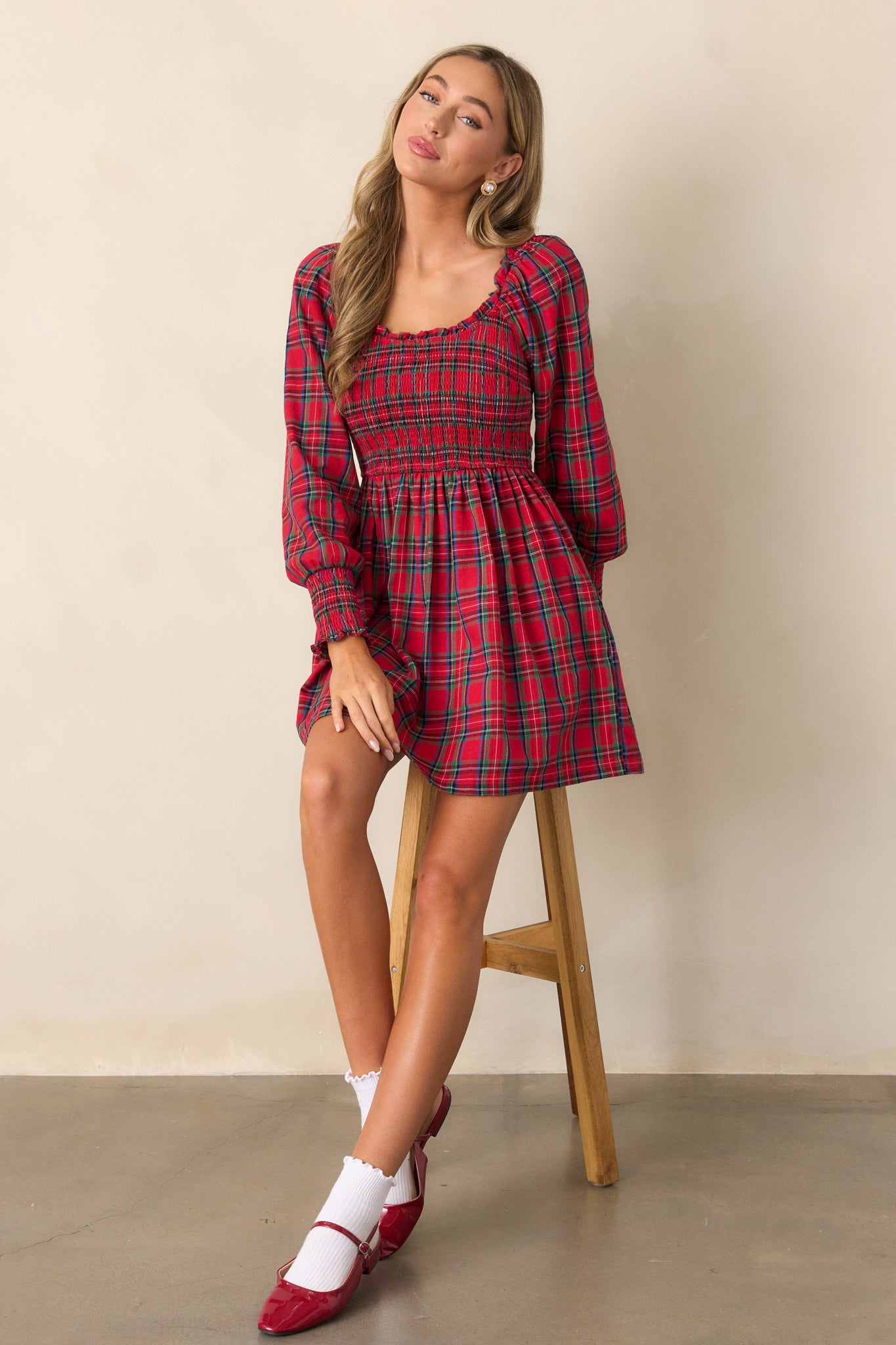 Front view of the red mini dress featuring a scoop neckline, ruffle trim detailing along the neckline, and a fully smocked bodice with a plaid print.