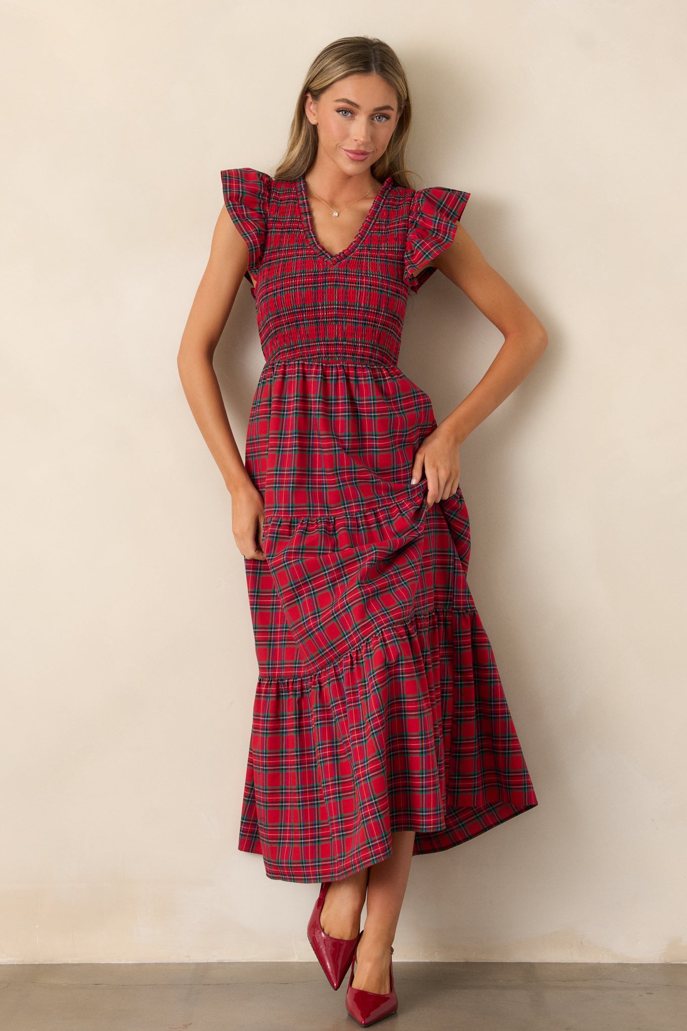 A red dress with a V-neckline, a fully smocked bodice, a tiered skirt, and flutter sleeves, shown from the front.