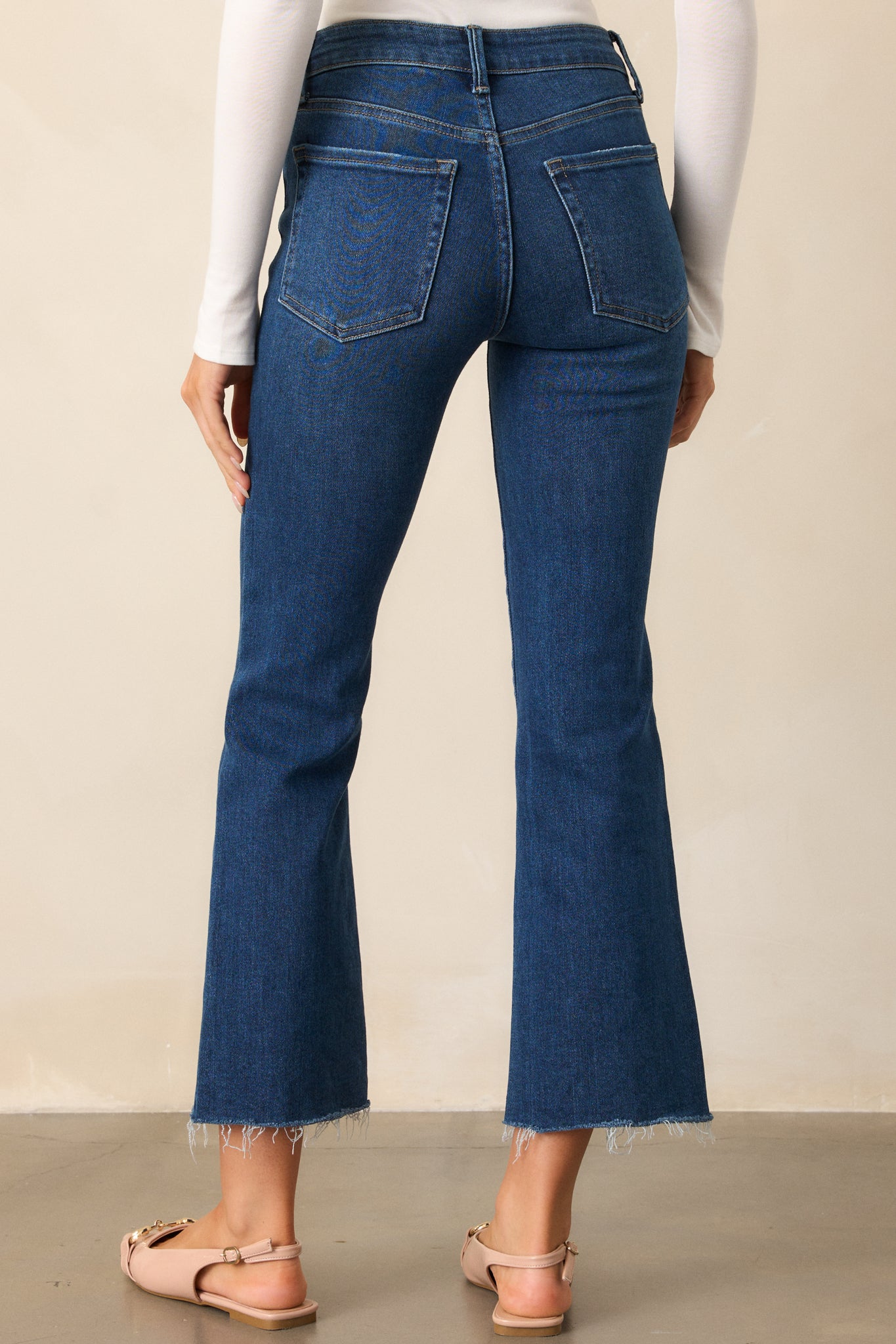 Back view of the dark wash jeans, highlighting the cropped hem and the fit around the hips and thighs, with the back pockets visible.