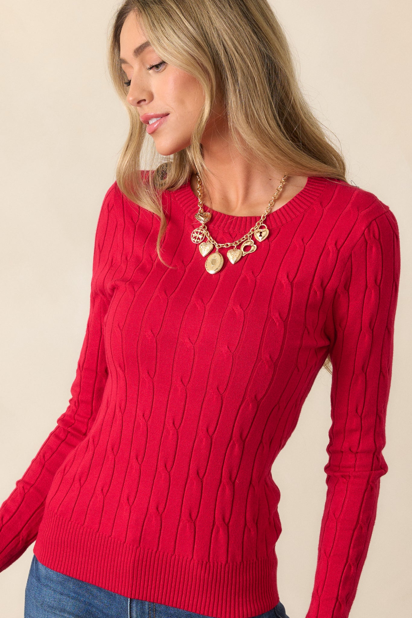 A cropped shot highlighting the bold red sweater's cable knit design and vibrant color close-up.