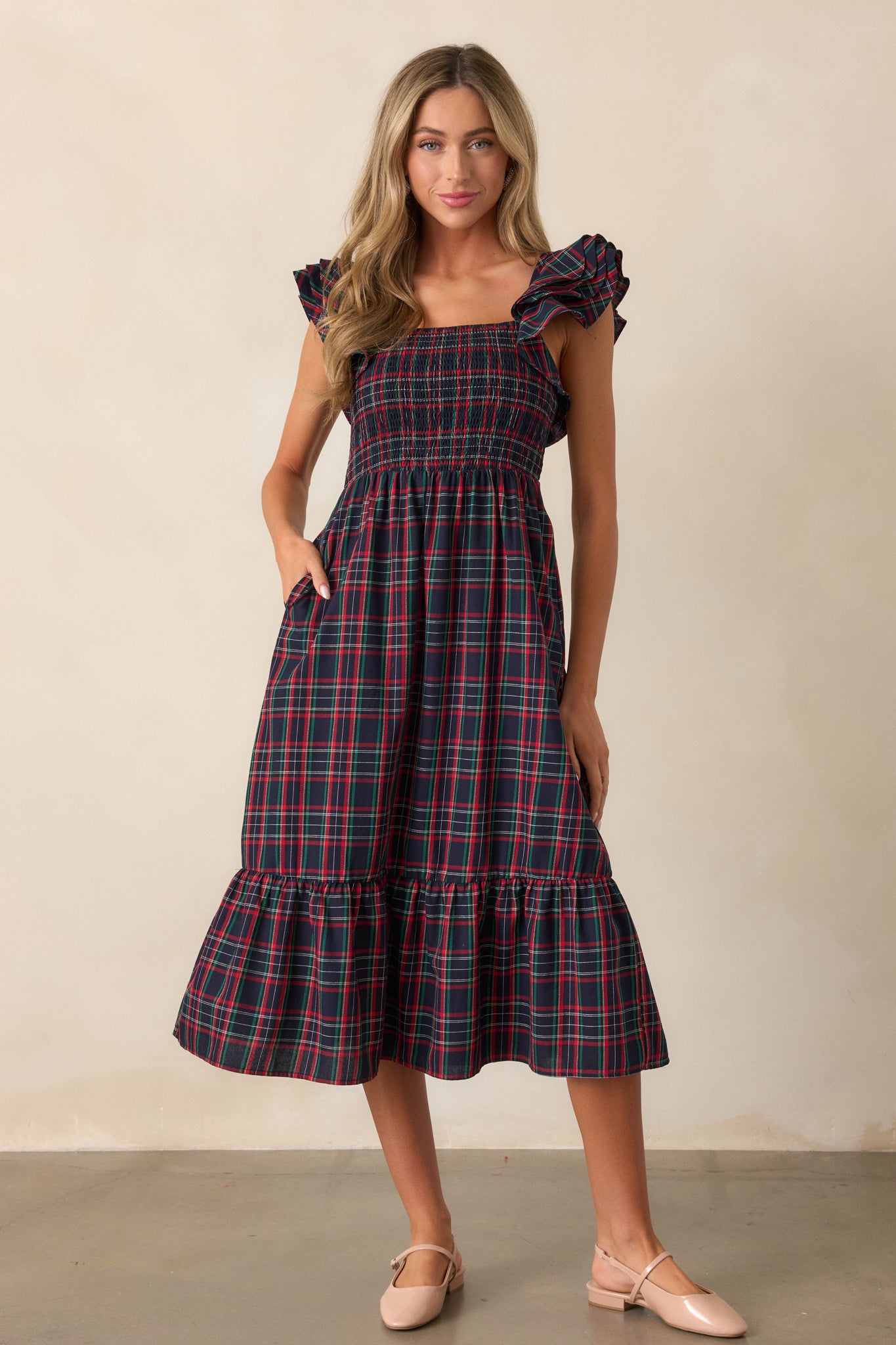 Full-length view of the navy dress highlighting the smocked bodice, flutter sleeves, and the layered tiers of the skirt.