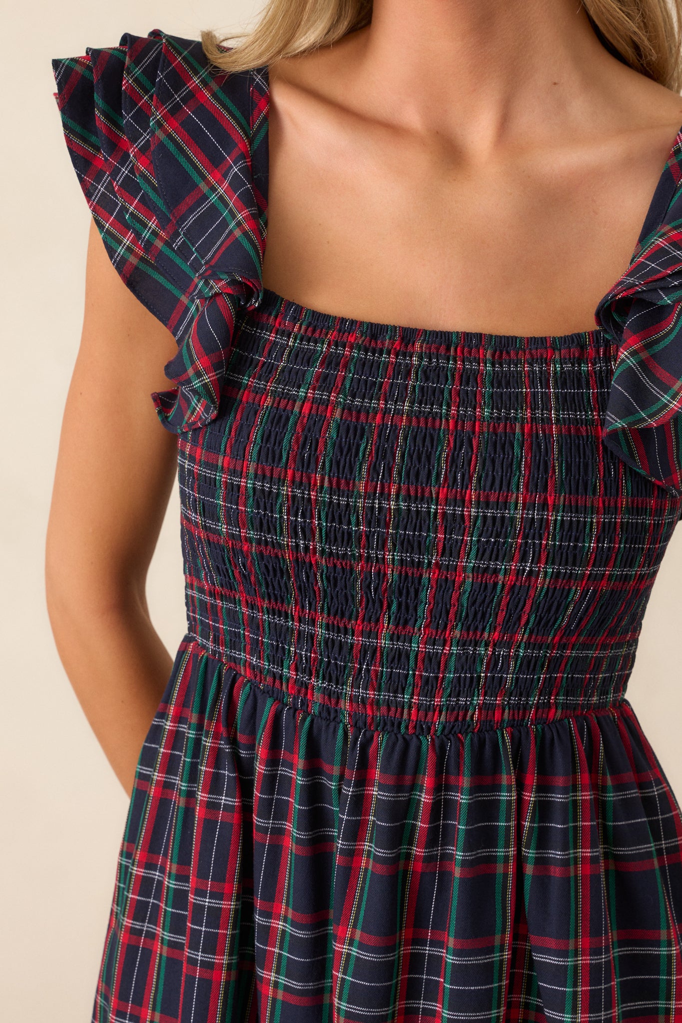 Close-up of the smocked bodice, highlighting the square neckline, plaid print, and delicate flutter sleeve details.